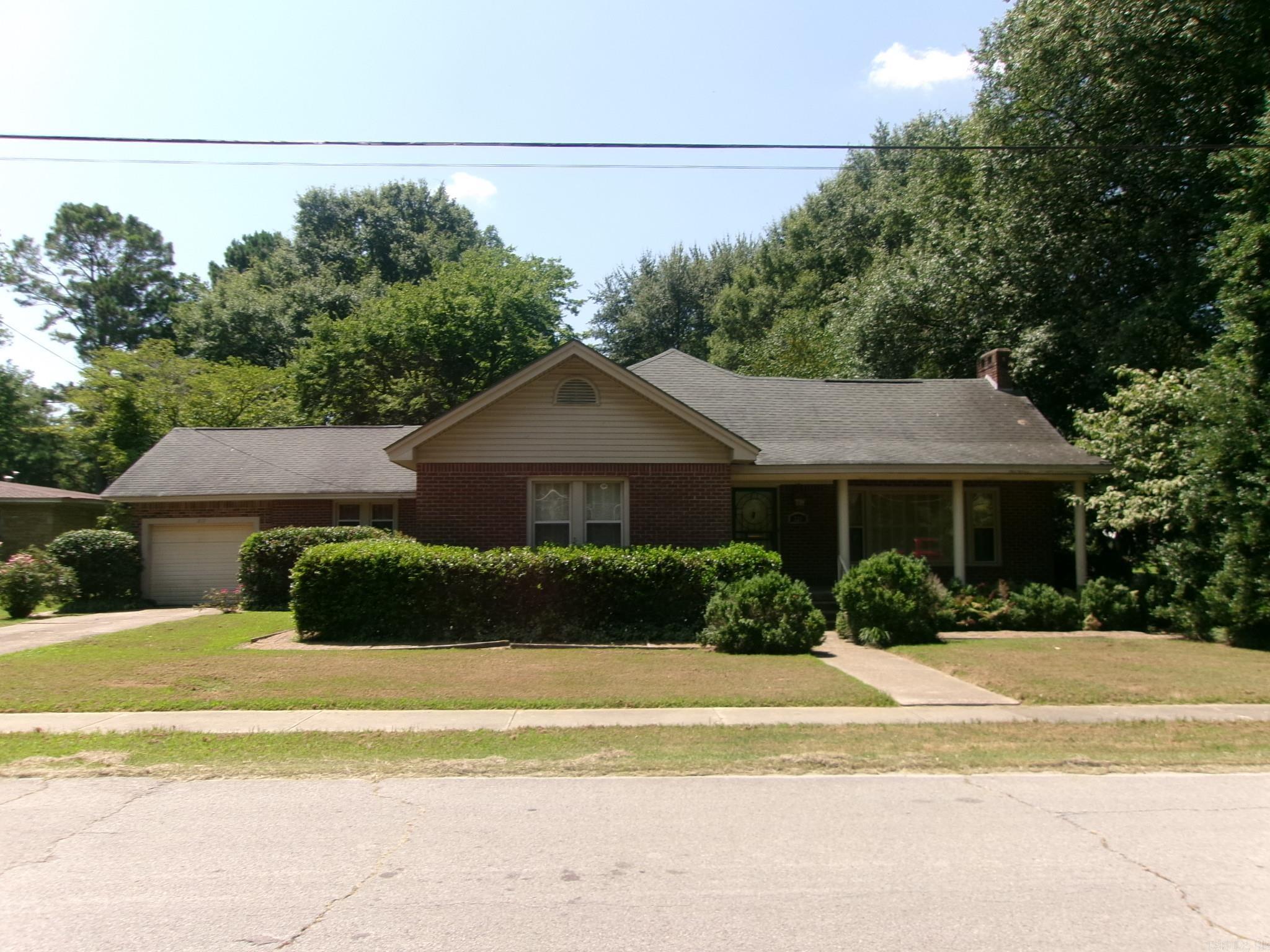 Well maintained older home on a corner lot with attached, fully enclosed, one-car garage. On 2 city lots with alley access behind the property, the house has a large, open concept living/dining space with a dual, wood burning/gas logs fireplace. All exterior entrances have wrought-iron security doors. Primary bedroom has a cedar lined closet and en suite half bath. Separate laundry room with utility sink. Custom made interior shutters on all the windows throughout. Oversized backyard has lots of grand pin oak trees, dogwoods and one mature magnolia tree for shade. At the back of the property, there’s an 864 sq ft barn-style workshop with red Hardee board siding, and pure, copper-top cupola with pure copper weathervane. Workshop has roughed-in pipework for a half bath, a wood burning stove and a very spacious loft with pull down stairs. Next to the workshop there is a separate well for outdoor watering.