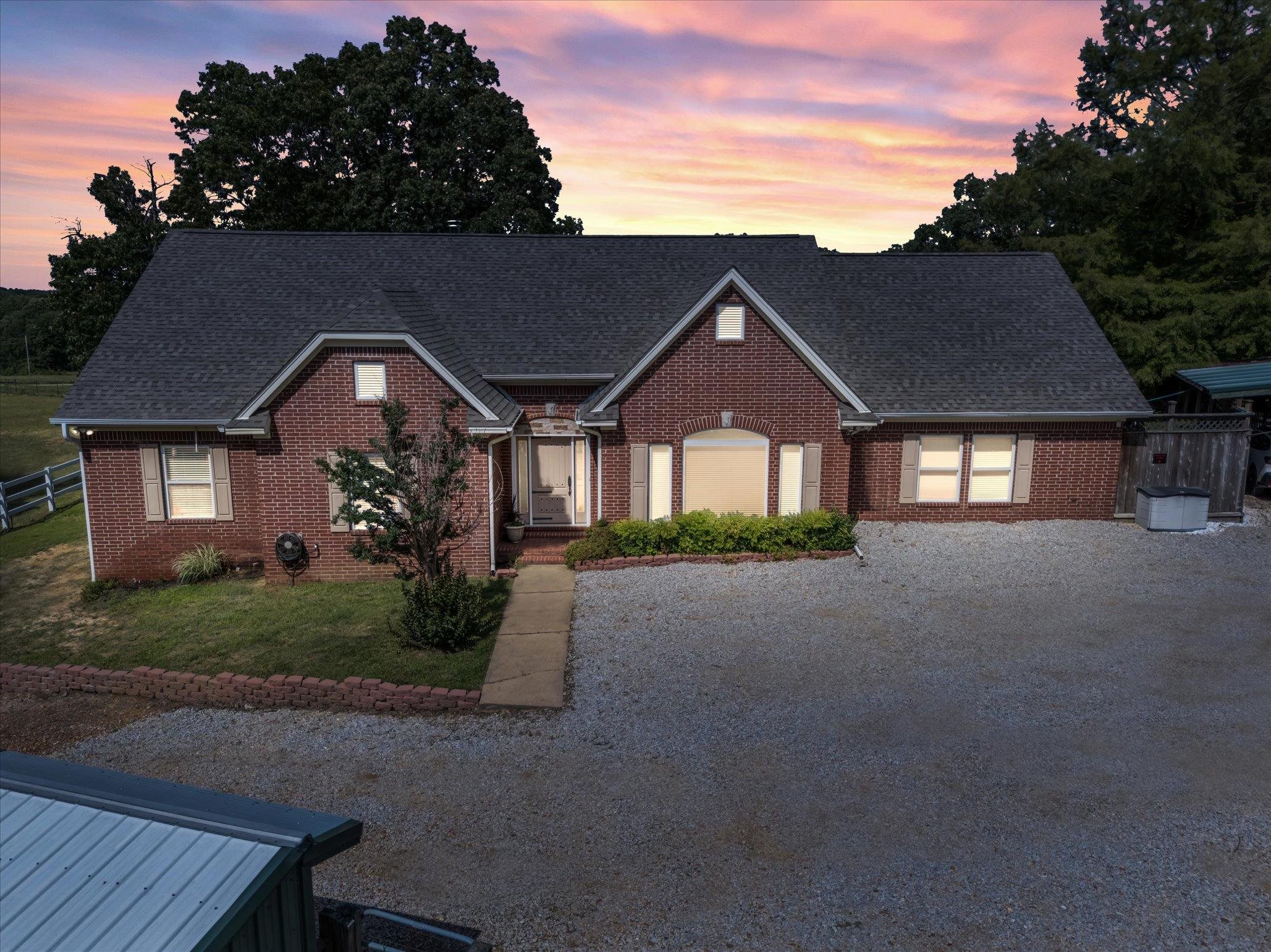 Ranch-style living on The Ridge! This fully fenced and gated 7.91-acre property is ready for horses, cattle, goats, chickens, and more...truly turn-key for any hobby farm or equestrian lifestyle. The land features a stocked 1/4-acre pond, a 48'x24' barn with three 12'x12' stalls and a tack/feed room, a 40'x25' additional barn, 12'x6' log shed, and a large 75'x30' shop with electric door. The entire perimeter is gated and fenced for privacy and livestock security. Inside, enjoy over 3,800 +/- Sq Ft with 3 spacious bedrooms and 2.5 baths on the main level. Highlights include vaulted ceilings, rich hardwood flooring, and two cozy wood-burning fireplaces. The oversized primary suite features a luxurious bath with soaking tub, walk-in shower, and dual vanities. The kitchen offers quartz countertops, abundant cabinetry, and connects to both a breakfast nook and a formal dining area. Fully finished walk-out basement perfect for guests and use as a storm shelter. Step out to the fully screened-in porch complete with a fireplace and dual grills. Many updates include a new roof in 2024. Offers the peace and privacy of the country and just 7.3 miles from the Jonesboro City limits. Tour today
