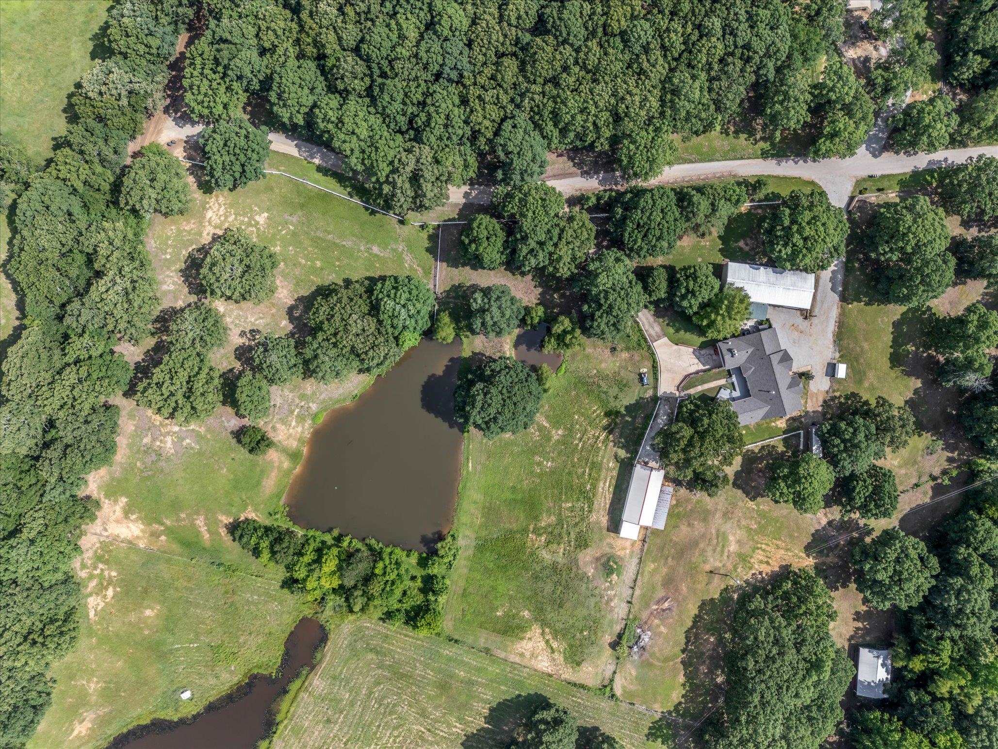 Ranch-style living on The Ridge! This fully fenced and gated 7.91-acre property is ready for horses, cattle, goats, chickens, and more...truly turn-key for any hobby farm or equestrian lifestyle. The land features a stocked 1/4-acre pond, a 48'x24' barn with three 12'x12' stalls and a tack/feed room, a 40'x25' additional barn, 12'x6' log shed, and a large 75'x30' shop with electric door. The entire perimeter is gated and fenced for privacy and livestock security. Inside, enjoy over 3,800 +/- Sq Ft with 3 spacious bedrooms and 2.5 baths on the main level. Highlights include vaulted ceilings, rich hardwood flooring, and two cozy wood-burning fireplaces. The oversized primary suite features a luxurious bath with soaking tub, walk-in shower, and dual vanities. The kitchen offers quartz countertops, abundant cabinetry, and connects to both a breakfast nook and a formal dining area. Fully finished walk-out basement perfect for guests and use as a storm shelter. Step out to the fully screened-in porch complete with a fireplace and dual grills. Many updates include a new roof in 2024. Offers the peace and privacy of the country and just 7.3 miles from the Jonesboro City limits. Tour today