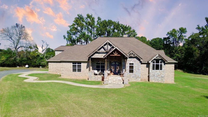 Escape to your own private meadow just outside the city limits on more than 6 acres of beautiful cleared pasture. This custom home blends rustic charm with modern comfort, offering an open concept design with soaring vaulted ceilings, rich wood tile floors, and inviting stacked stone fireplaces in the living room and primary suite. Wraparound porches create the perfect setting to relax or entertain while enjoying peaceful views. The gourmet kitchen is a dream with magma gold leathered granite, a Wolf range with pot filler, copper sink, Frigidaire Pro fridge and freezer, and a Sonic ice maker. Every bathroom is a retreat with custom tile work, bowl sinks, and raw edge counters, while the primary suite has private French doors and a serene spa bath with travertine tile. A 40x60 red iron shop, whole home Generac generator, spacious laundry with extra storage, instant hot water, and a walk in attic complete this thoughtfully designed home.