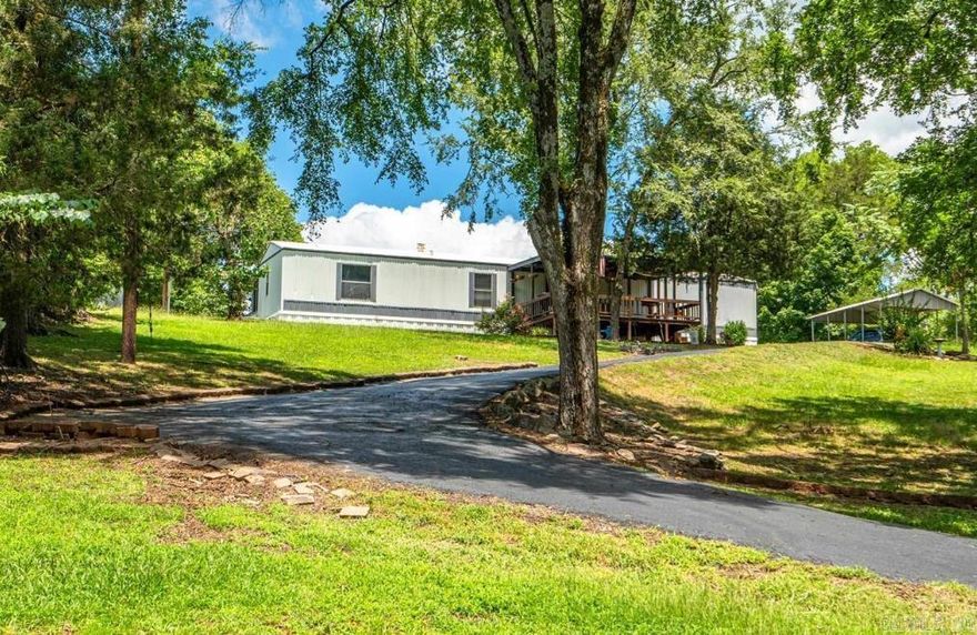 Discover the perfect blend of comfort, privacy, and functionality in this delightful 3 bedroom, 2 bath single wide mobile home nestled on almost 2 acres of picturesque, pristine land. Boasting a large cinder block workshop with plumbing, this property is ideal for those seeking a versatile space for hobbies, projects, or storage. Upon arrival, you'll be greeted by a picturesque landscape of lush greenery and mature trees that envelop the property, offering a serene retreat from the hustle and bustle of everyday life ensuring privacy and a sense of seclusion. A spacious front porch welcomes you to relax and take in the tranquil surroundings, perfect for morning coffee or evening stargazing. Inside, the home boasts a kitchen with the adjoining living area that features windows that showcase the natural beauty of the surroundings. The primary bedroom provides a peaceful retreat with an ensuite bathroom for added convenience. Two additional bedrooms offer flexibility for guests, a home office, or hobbies, ensuring everyone has their own space. Step outside to explore the expansive yard, where possibilities abound. Move-in-ready for your convenience as this home comes furnished.