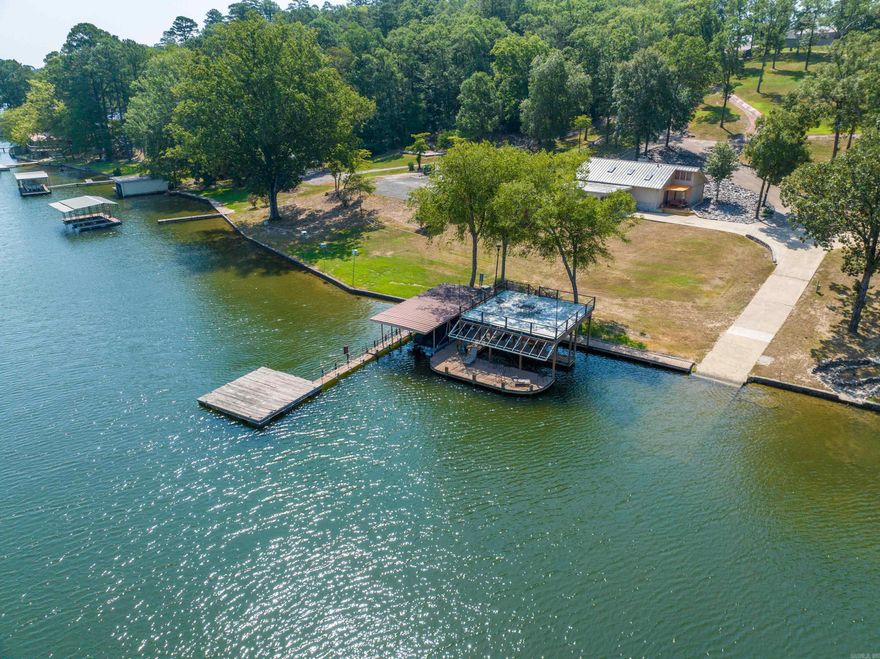 This exceptional lakefront property on the highly sought-after south shore of Lake Hamilton offers a rare combination of natural beauty,development potential, and luxurious amenities. Spanning approximately 4.25 acres with 226 feet of pristine shoreline, the land featuresmultiple building sites both on and off the water, making it ideal for a private compound or a boutique residential development. A naturalwaterfall cascades from the top of the property down to the lake, flowing past exposed rock formations embedded with authenticdinosaur fossils—an extraordinary and unique natural element rarely found anywhere. At the water’s edge, the property is fully equippedfor lakefront living with three covered boat slips, a private boat launch, a large swim platform, and two party decks including an expansiveentertaining area atop one of the docks. The estate is gated for privacy and includes the Pinehill House, a well-appointed residencefeaturing Viking and Sub-Zero appliances, Madrid quartz flooring, a recently updated roof (2023), new skylights and gutters, and a two-car garage with workshop space. A newer high-efficiency AC system ensures year-round comfort. Whether you’re looking for a