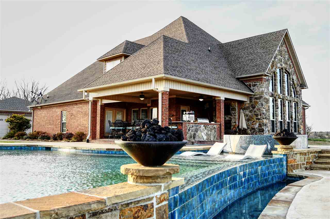 This STUNNING home is a MUST SEE! Sitting on top of the hill over looking 3 ponds on just over 56 acres The home has 3 bedrooms, Huge master that opens out to the outdoor kitchen, infinity pool & hot tub! Office, Workout room with safe room, Upstairs are two bedrooms with their own bathrooms, theater room with concession stand room! Attached is a 3 car, and motorcycle garage! Detached is a 6 car garage with office and full bath!Also detached is a large shop with bar, full bath, loft, deck on back!