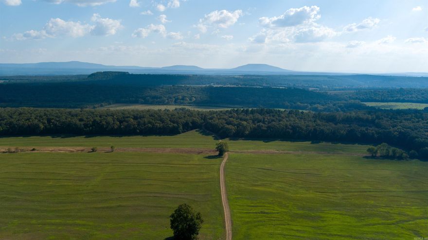 This property is a rare find, spanning a substantial 1287 acres. I have thoroughly explored the land, and it truly is a hunter's paradise, featuring open fields along the Petit Jean River and backing up against the mountains. Currently, all the fields have been cut for hay. During our last visit, I noticed that the fields had just been hayed, attracting all kinds of wildlife. Quail would be a great addition to this property; in fact, there are already a few present, along with deer. The wooded areas also invite turkeys. Accessing the roads leading to, through, and from the property is easy. Additionally, there are several sheds on the property that are used for storing tractors and hay—just minutes from conveniences in Booneville.  If you want to build your dream lodge, the site is just a short distance from Fort Smith's shopping area.  Don't miss out on this opportunity, and as the country and western song says, "Buy Dirt."  Last count on large round bales of hay was 835+