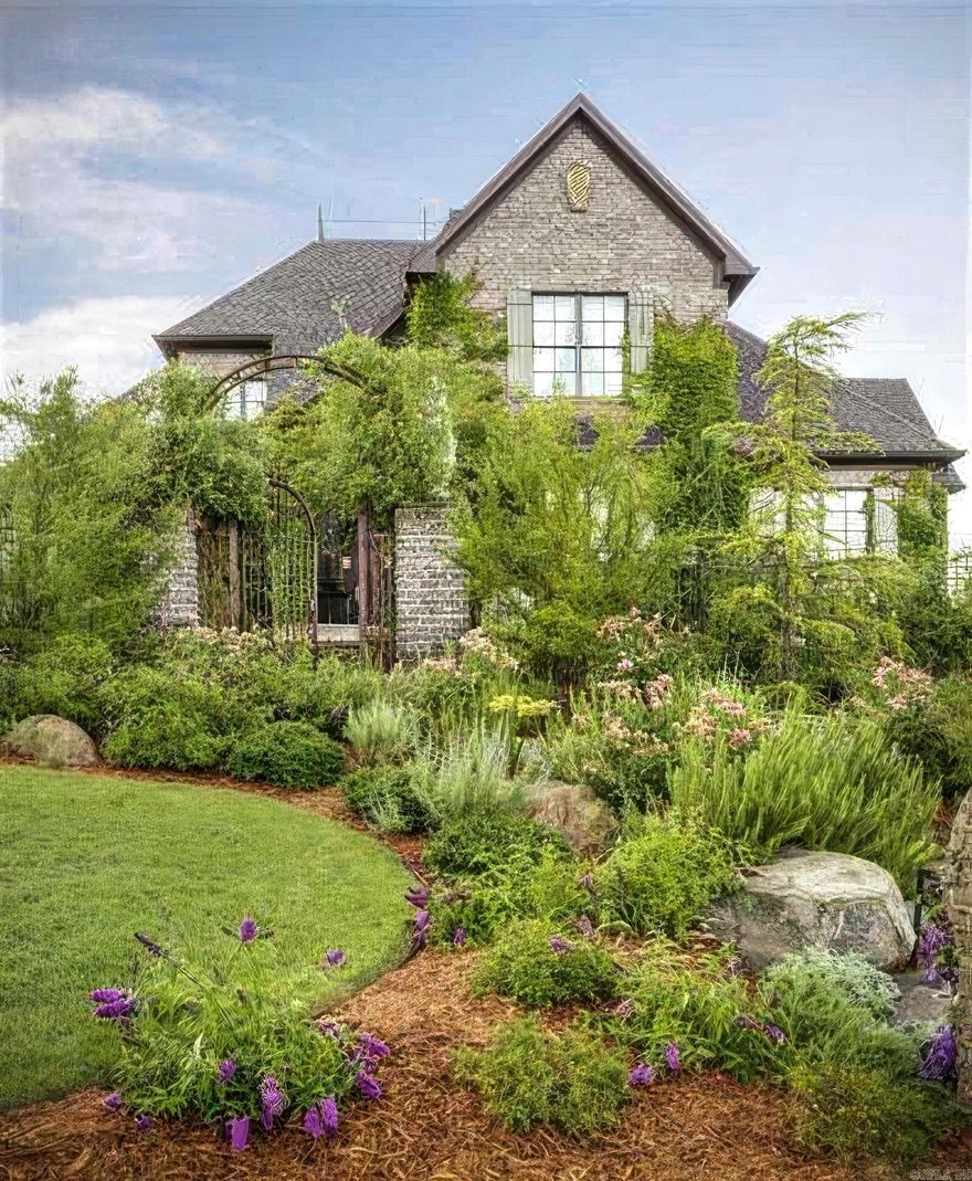 Welcome to 16206 Vista Del Rio — a stunning French Country hilltop estate in gated Mountain Crest Estates. Perched above the Maumelle area, this home captures breathtaking views of the Arkansas River, Pinnacle Mountain, and the distant mountain range from nearly every room. Step into the grand foyer, leading to a soaring 21-foot ceiling living room anchored by a dual-sided fireplace and walls of windows that frame the remarkable landscape. The chef’s kitchen features Alaskan White marble countertops and backsplash, perfect for both daily living and entertaining. The primary suite offers a serene sitting area and a spa-like bath that feels like a royal retreat. Upstairs, two spacious bedrooms share a Jack and Jill bath, while the oversized theater room with projector and screen provides the ultimate movie night experience and could be a 4th bedroom. Outside, enjoy enchanting gardens, a greenhouse, and wraparound porches along the western side of the home—ideal for sunset views and peaceful relaxation. Experience timeless elegance and natural beauty in this extraordinary Maumelle estate. Schedule your showing today!