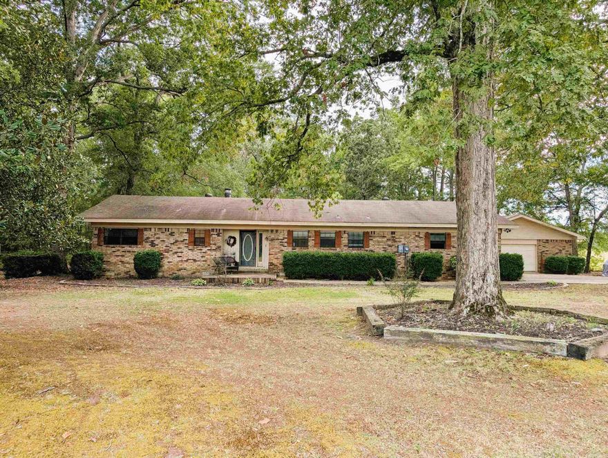 Escape to your own private slice of the countryside with this charming ranch-style brick home, perfectly situated on a peaceful 1.40-acre lot. Mature shade trees canopy the property, creating a tranquil, secluded feel that makes you forget you're just a 12-mile drive from town. Enjoy the best of both worlds: genuine privacy without sacrificing easy access to amenities.  This classic home features 3 comfortable bedrooms & 2 full bathrooms. The primary suite has a open concept but can easily be enclosed for more privacy. The heart of the home is a spacious, L-shaped eat-in kitchen, with built-in cabinets featuring glass fronts—perfect for displaying your favorite dinnerware. The kitchen also hosts the convenient laundry area. Entertaining is a breeze with the exceptionally large living room and an equally spacious formal dining room, providing ample space for gatherings and dinner parties.  Step outside to a large, open backyard, ideal for activities, gardening, or just enjoying the quiet country air. A covered back porch offers a wonderful spot for morning coffee or evening relaxation, and a dedicated storage building provides excellent space for tools and outdoor equipment.