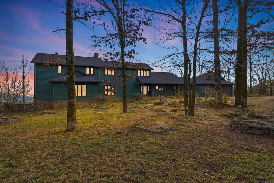 Perched high on Petit Jean Mountain with sweeping panoramic views of the Arkansas River Valley, this custom-built retreat offers the perfect blend of rustic elegance and modern comfort. Situated on 2.51 private, wooded acres, this home features 4 bedrooms and 3.5 baths designed for both everyday living and memorable getaways. Inside, soaring ceilings, rich hardwood and tile flooring, and abundant natural light create an inviting atmosphere. The spacious living room offers a cozy gas-log fireplace and a dramatic wall of windows that perfectly frame the breathtaking valley views. The kitchen showcases granite tile countertops, stainless steel appliances, generous cabinetry, and flows effortlessly into a dining area overlooking the scenic landscape. The primary suite has vaulted ceilings, a private balcony, and a spa-inspired en-suite bath. Upstairs, you’ll find additional bedrooms, a bunk room, and a versatile loft space. Outdoor living shines with an expansive deck made for sunset watching, entertaining, or simply soaking in the mountain serenity. Located just minutes from Petit Jean State Park, this property is ideal as a primary residence, vacation escape, or a short term rental!