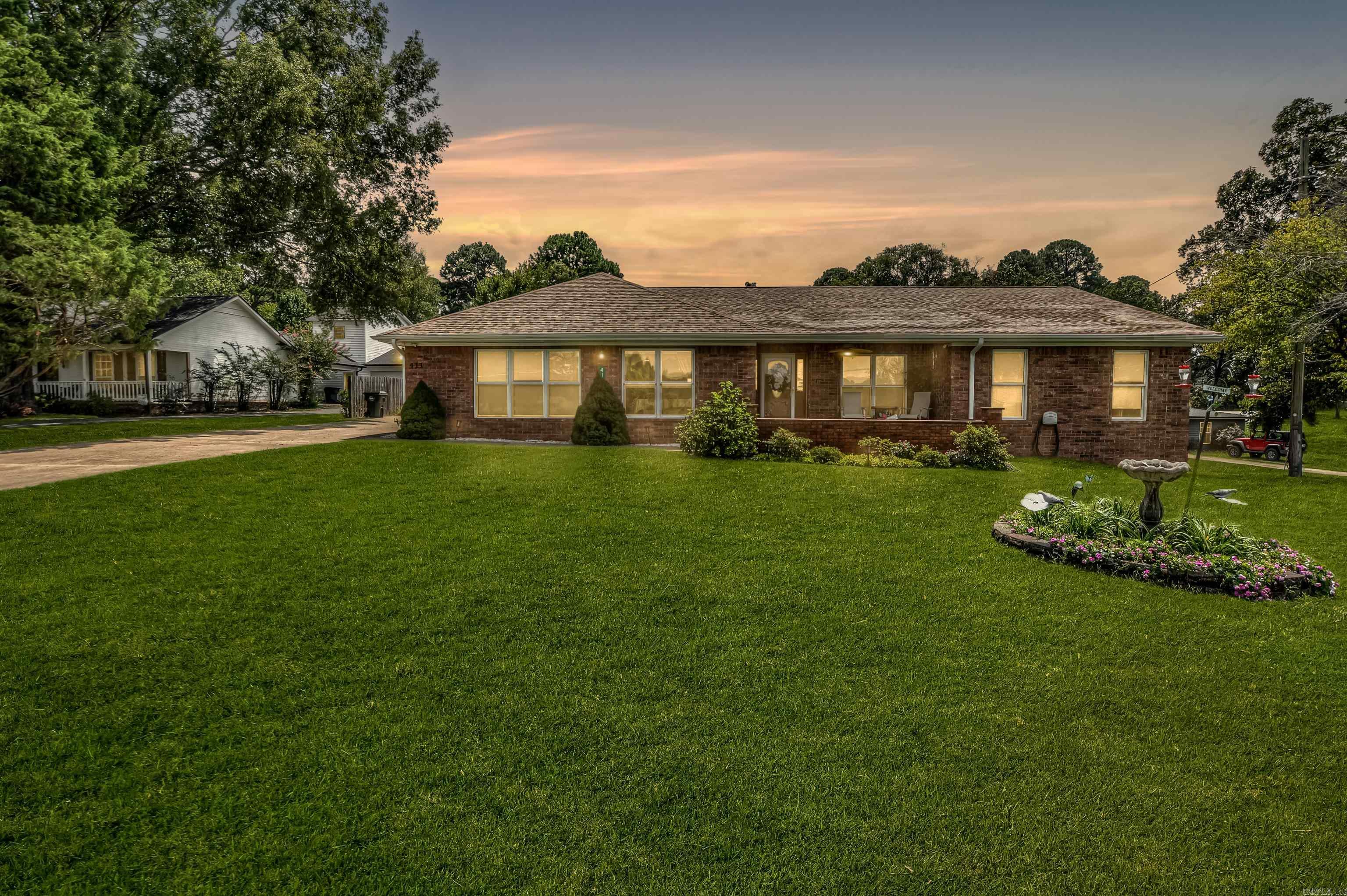 With lake views across the street and a history of welcoming guests, this home is as inviting as its location.This home sits on a gently sloping .54-acre lot and enjoys views of Lake Hamilton without the lakefront price tag. Over the years, it has been thoughtfully used as a respite home for pastors, offering the perfect floor plan for hosting gatherings and welcoming guests. Inside youāll find a spacious living room that flows into the dining and kitchen area, a formal dining room, and a second large family room, all designed to accommodate both everyday living and entertaining. The wide hallways and nearly step-free layout make the home versatile for many uses, even lending itself to group care or multi-generational living. Additional features include a detached two-car garage connected by a covered breezeway, a detached workshop, and a fully fenced backyard. Natural light fills the home through several sun pipes, while trayed ceilings with inset lighting add a touch of character. With its history of hospitality, timeless design, and unbeatable location just steps from the Fish Hatchery and Lake Hamiltonās boat ramp, this property offers both charm and endless potential.