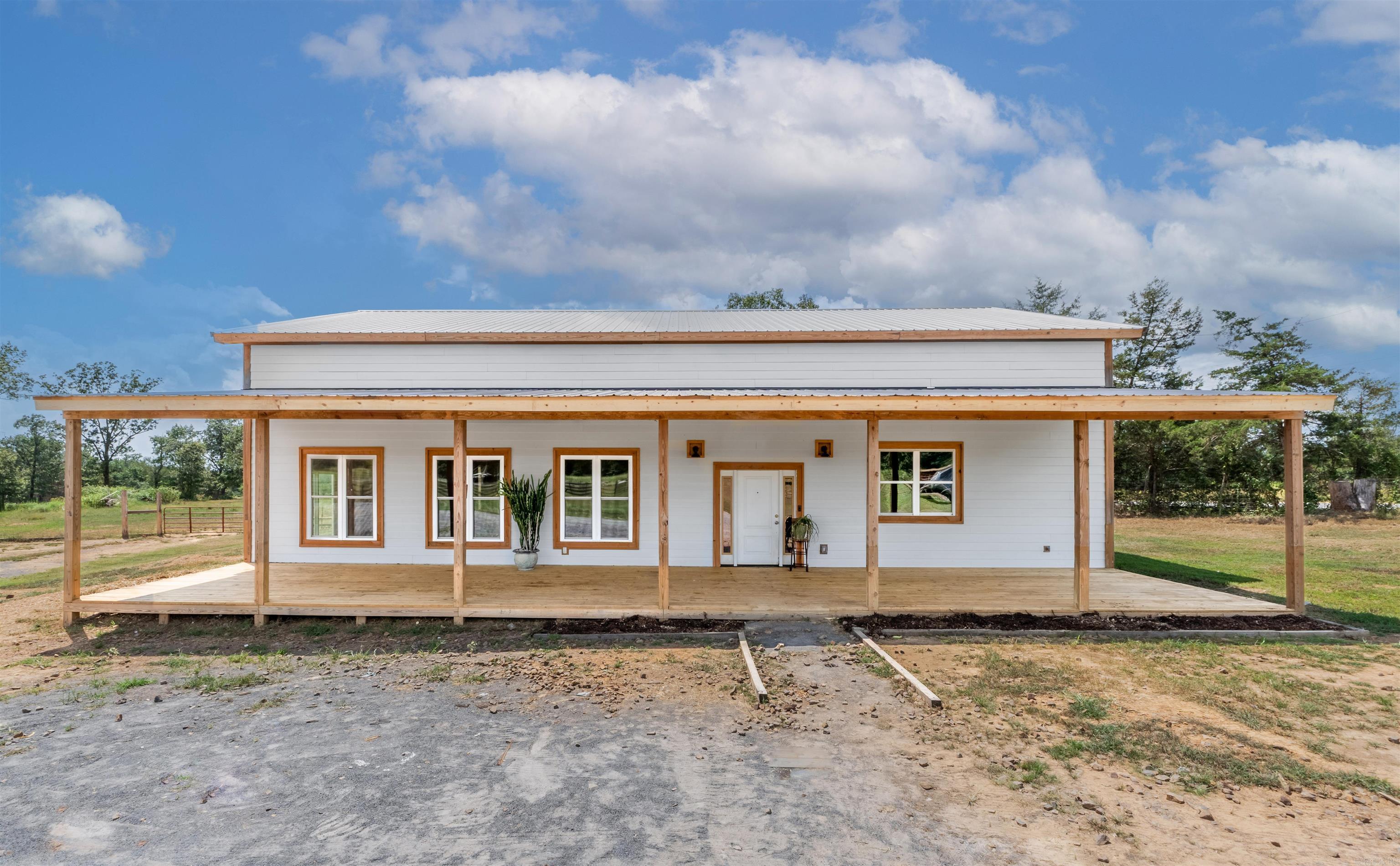 This modern farmhouse, built in 2022, sits on 30± acres of mostly open pasture with some wooded areas near the Ozark National Forest. The 3,200 sq ft home features vaulted ceilings, an open floor plan, and large covered porches on the front and back. The main-floor primary suite includes a walk-in closet and a custom walk-in shower for two. One additional bedroom is on the main level; two bedrooms upstairs each have a private full bathroom with tubs. The kitchen, renovated in 2025, has butcher block countertops and a spacious 5x20 ft walk-in pantry. The home showcases a variety of Arkansas hardwoods, including maple, walnut, cherry, sassafras, oak, sycamore, and cypress. A cedar tree harvested from the property was milled into a support post in the kitchen. The home sits on a monolithic slab with a metal roof, energy-efficient mini-split HVAC, LED lighting, and smart home tech. The fenced 30± acres include two pastures, two ponds, a spring-fed pond, and a 40x60 pole barn. Utilities include public water, septic, fiber internet, and strong cell service.This property is well-suited for livestock with productive ranch land ready for immediate use. One-year home warranty included.