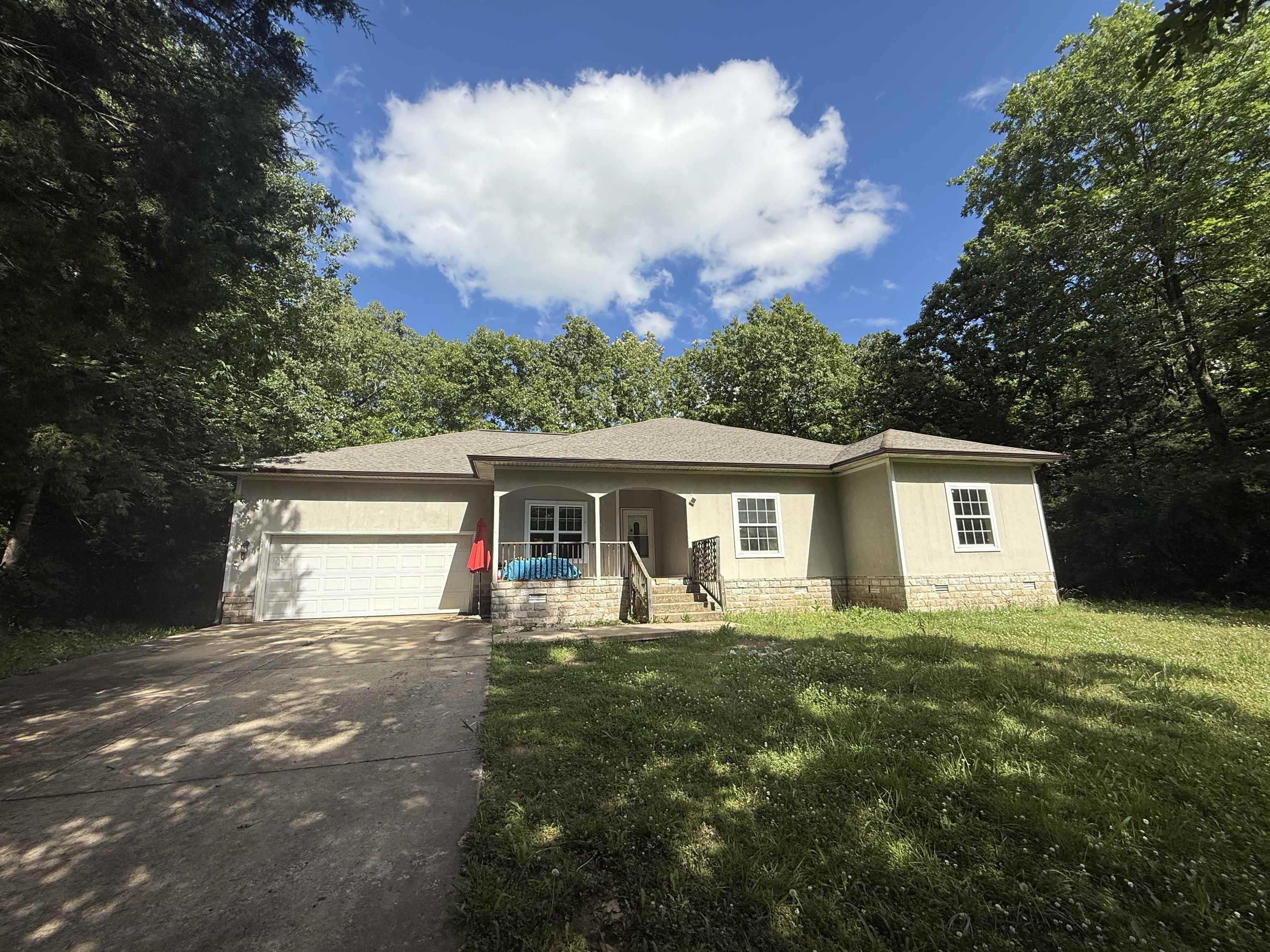 This charming three-bedroom, two-bath home is ideally located less than a mile from the main entrance of Cherokee Village. Built in 2007, it sits on a private, wooded lot, offering peace and privacy while remaining conveniently close to town. The home features a concrete driveway, a one-car garage with interior access, and two inviting covered porches—perfect for enjoying the natural surroundings. Inside, you’ll find new vinyl flooring throughout most of the home, with tile in the kitchen and main bathroom. High ceilings add to the spacious, open feel of the living areas. The primary bedroom includes a walk-in closet and a large bathroom complete with a jetted tub and a beautifully tiled walk-in shower. The hall bath features a standard tub/shower combo for added convenience. While the Trane HVAC unit is currently not operational, this 18-year-old home has solid bones and great potential. With a little TLC, it could be a wonderful full-time residence or a relaxing retreat in the heart of Cherokee Village.