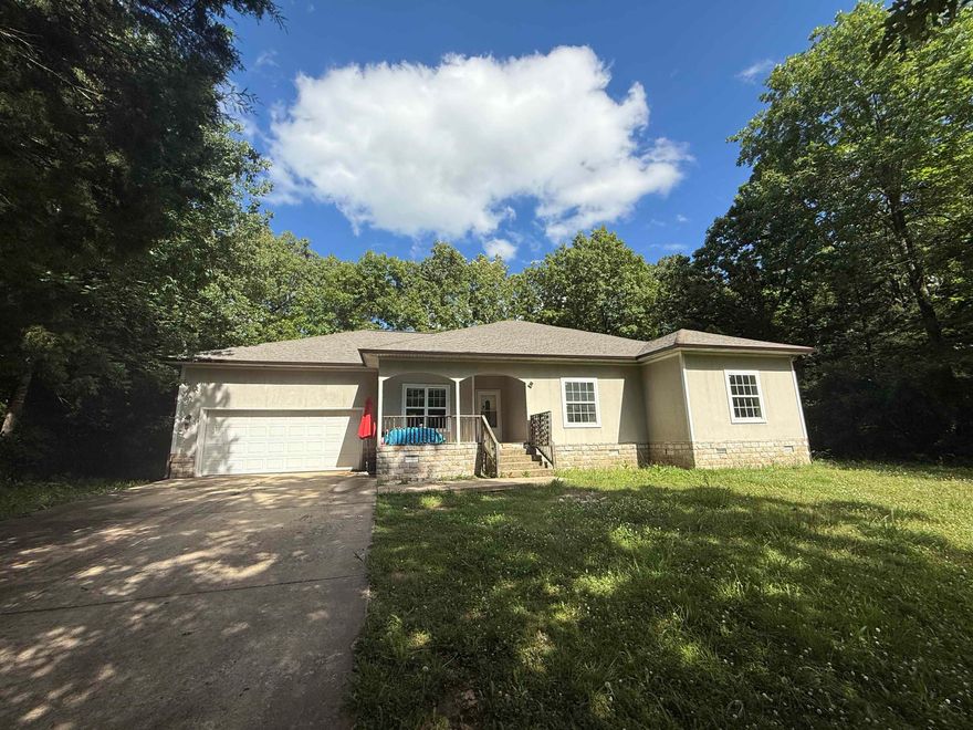 This charming three-bedroom, two-bath home is ideally located less than a mile from the main entrance of Cherokee Village. Built in 2007, it sits on a private, wooded lot, offering peace and privacy while remaining conveniently close to town. The home features a concrete driveway, a one-car garage with interior access, and two inviting covered porches—perfect for enjoying the natural surroundings. Inside, you’ll find new vinyl flooring throughout most of the home, with tile in the kitchen and main bathroom. High ceilings add to the spacious, open feel of the living areas. The primary bedroom includes a walk-in closet and a large bathroom complete with a jetted tub and a beautifully tiled walk-in shower. The hall bath features a standard tub/shower combo for added convenience. While the Trane HVAC unit is currently not operational, this 18-year-old home has solid bones and great potential. With a little TLC, it could be a wonderful full-time residence or a relaxing retreat in the heart of Cherokee Village.