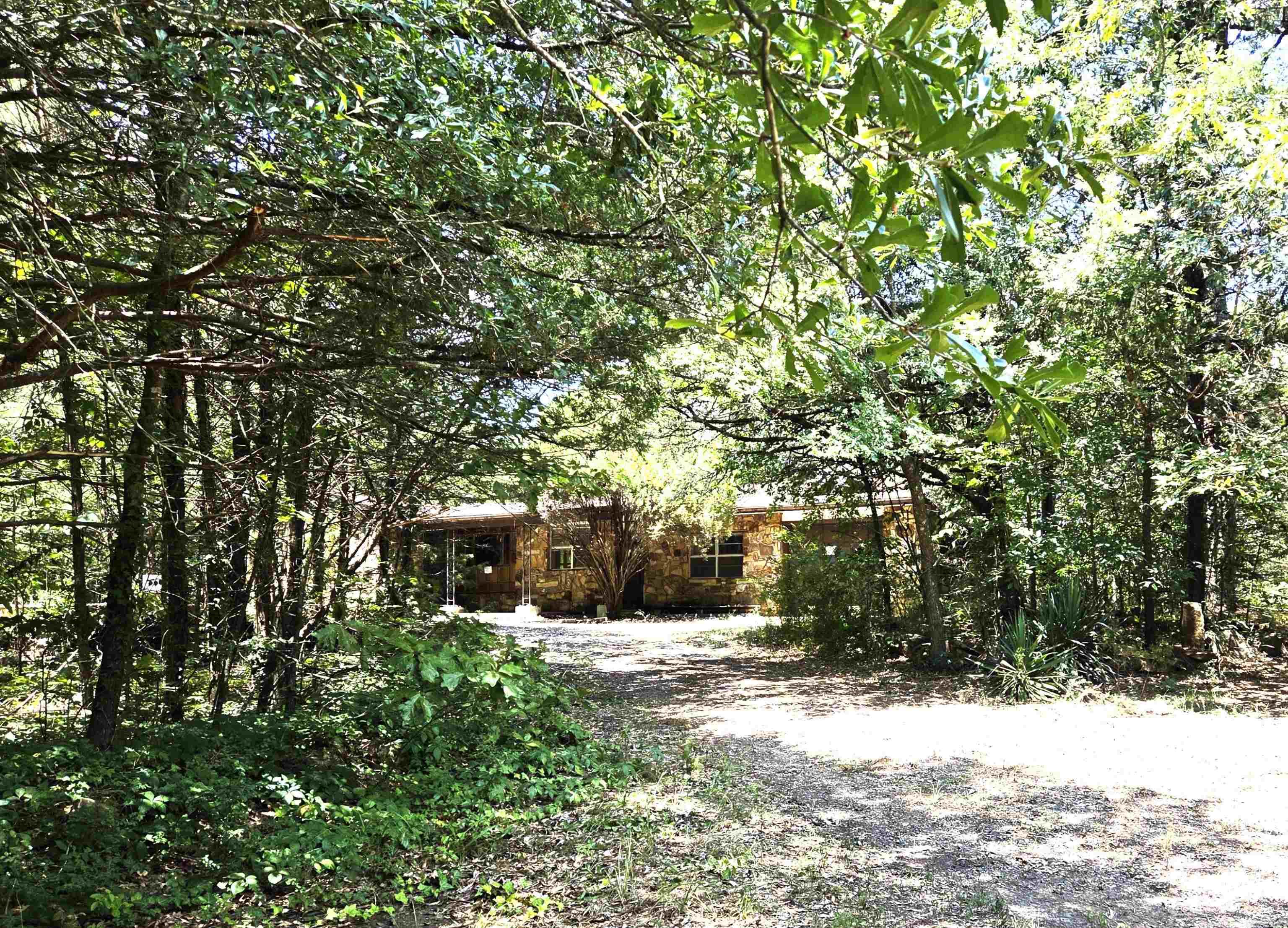 Amazing location with almost 3 acres of wooded land and a charming rock and frame home needing the right person to restore it to its prior livable condition. Yes, it is a definite fixer-upper but has all of the elements to remodel it to it's former glory. The floor plan is split with two bedrooms and a bath in one wing, and the primary bedroom on the opposite side of the living, kitchen, dining spaces. Laundry, bonus room, and a one car garage. Shop. Storage shed. Circle driveway. This one is a little gem waiting to be discovered. Agents see remarks