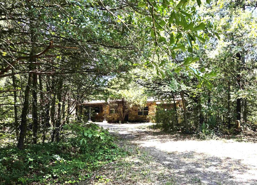 Amazing location with almost 3 acres of wooded land and a charming rock and frame home needing the right person to restore it to its prior livable condition.   Yes, it is a definite fixer-upper but has all of the elements to remodel it to it's former glory. The floor plan is split with two bedrooms and a bath in one wing, and the primary bedroom on the opposite side of the living, kitchen, dining spaces.  Laundry, bonus room, and a one car garage.  Shop.  Storage shed.  Circle driveway.  This one is a little gem waiting to be discovered.  Agents see remarks