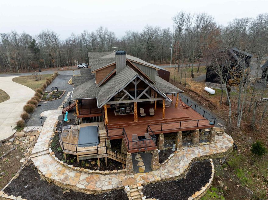 This architectural masterpiece of rugged elegance commands panoramic, unobstructed views of Greers Ferry Lake and the timeless Ozark Mountains. This 2,468 sq ft log-style showpiece blends mountain craftsmanship with refined luxury, offering a front-row seat to sapphire waters and endless horizons—just minutes from top marinas. Walls of windows and soaring wood ceilings bathe the open living spaces in natural light, centered by a dramatic wood-burning fireplace that flows seamlessly to a second outdoor hearth on the expansive wraparound decks. The gourmet chef’s kitchen dazzles with granite counters, a full-size butler’s pantry, double ovens, gas convection range, and a grand island perfect for gatherings. All Bedroom suites all feature spa-like walk-in shower. Descend to the walkout lower level or indulge in the endless swimming pool, delivering resort-style currents against a breathtaking lake backdrop. Uncompromising quality throughout: Perma-seal encapsulation on the entire home, whole-house Generac generator, automated blinds, fiber internet, and a handicap-accessible entryway. This is not just a home—it is a legacy sanctuary of unparalleled craftsmanship and timeless beauty.