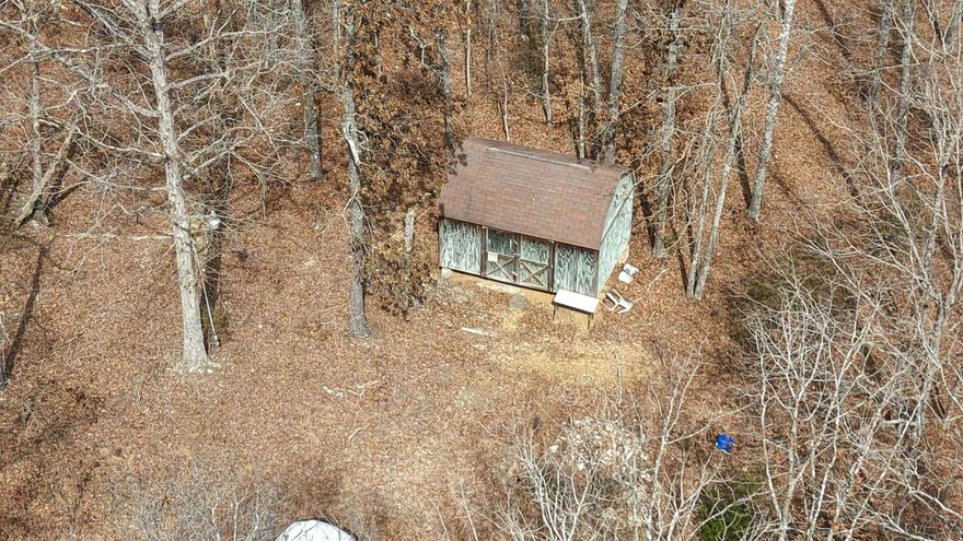 This 20± acre tract in the Reeds Bluff Addition offers a great opportunity for a hunting retreat, homestead, or hobby farm near Evening Shade and Ash Flat in north-central Arkansas. The property is mostly wooded with a mix of hard woods and evergreens, providing natural privacy, shade, and habitat for wildlife. The land includes a 12x16 portable building that can be used for storage, a small hunting cabin setup, or a base camp while you develop the property. A native stone fire pit adds a rustic gathering spot for cooking out, relaxing after a day in the woods, or enjoying evenings under the stars.  Landowners in this subdivision enjoy private access to a park on the Strawberry River, offering opportunities for fishing, swimming, floating, and relaxing by the water just a short distance away. High-speed fiber optic internet is available in the area, making it easier to work remotely or stay connected while living in the country. Electricity is located at the entrance to the property, and rural water is available approximately half a mile away, giving buyers a head start on utilities when planning future improvements. This versatile Sharp County acreage is listed for $79,900.