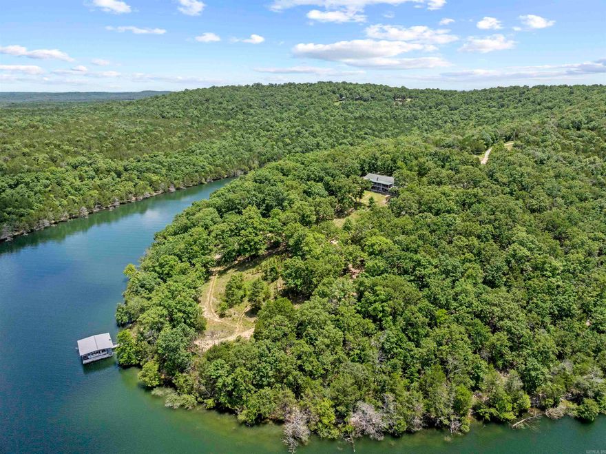 A rare opportunity—62± acres on a private peninsula, surrounded by Bull Shoals Lake on three sides. Unmatched privacy, panoramic views, & direct lake access set the stage for lake life at its best. The fully furnished 3-bed, 3-bath home is made for relaxing & entertaining, with a wraparound deck. The walk-out basement offers a second living area, bonus room, storm shelter, kitchenette, & hot tub. Your private two-stall dock with lifts conveys—a rare find on Bull Shoals, where no new dock permits are issued. Both boats can convey with an acceptable offer—lake days start instantly. The land offers a mix of woods, clearings, trails, wildlife, & multiple build sites—perfect for a family retreat, vacation compound, or future development. Extras: detached 2.5-car garage with studio apartment, carport for boat storage, & an outdoor shower. Just 10 minutes from Lead Hill & 5 minutes from the nearest boat ramp at the end of Camp Galilee Rd (MC 2061). Secluded yet accessible—a legacy property like no other.