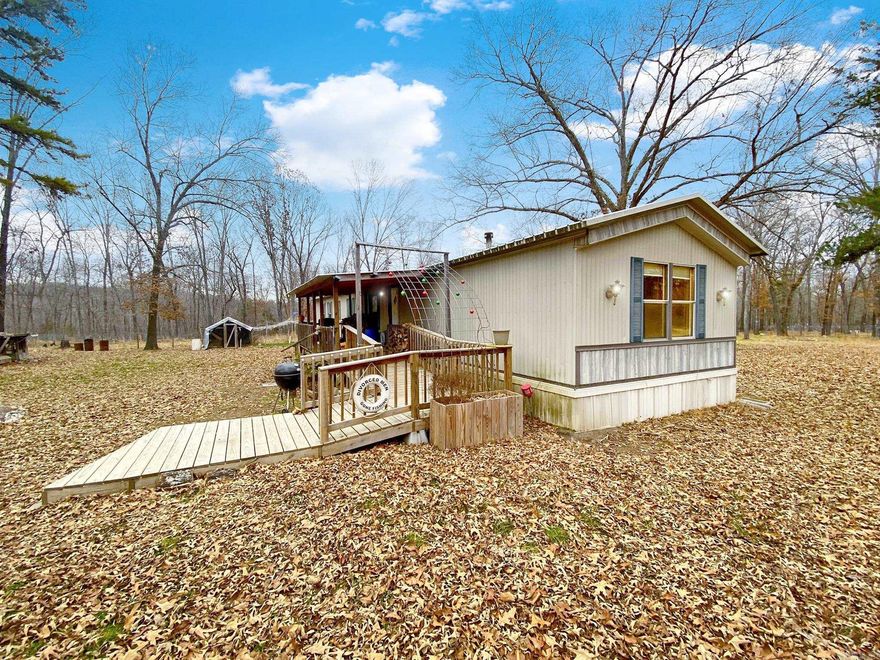 This private country 3 bedroom/2 bath retreat, sitting on an 8.23 ac/ml level mostly cleared lot has many outdoor features to enjoy. A 20x20 steel framed workshop, 2 storage buildings with electric, divided turkey & chicken pens, and a comfortable deer stand, overlooking a deer food plot, flower beds, spirit tree, fenced in garden, tree swing, plus a storm shelter. The handy cap ramp leads up to the large covered front porch with a metal roof. Inside you will find that the open floorplan features a wood burning stove & a well-designed kitchen that makes for easy entertainment.  Vaulted ceilings throughout, a split bedroom plan with a walk-in shower in the master, plus a separate laundry room makes for easy living. Located only 3 miles from the White River access, & close to Crooked Creek makes this one a great location for outdoor fun.