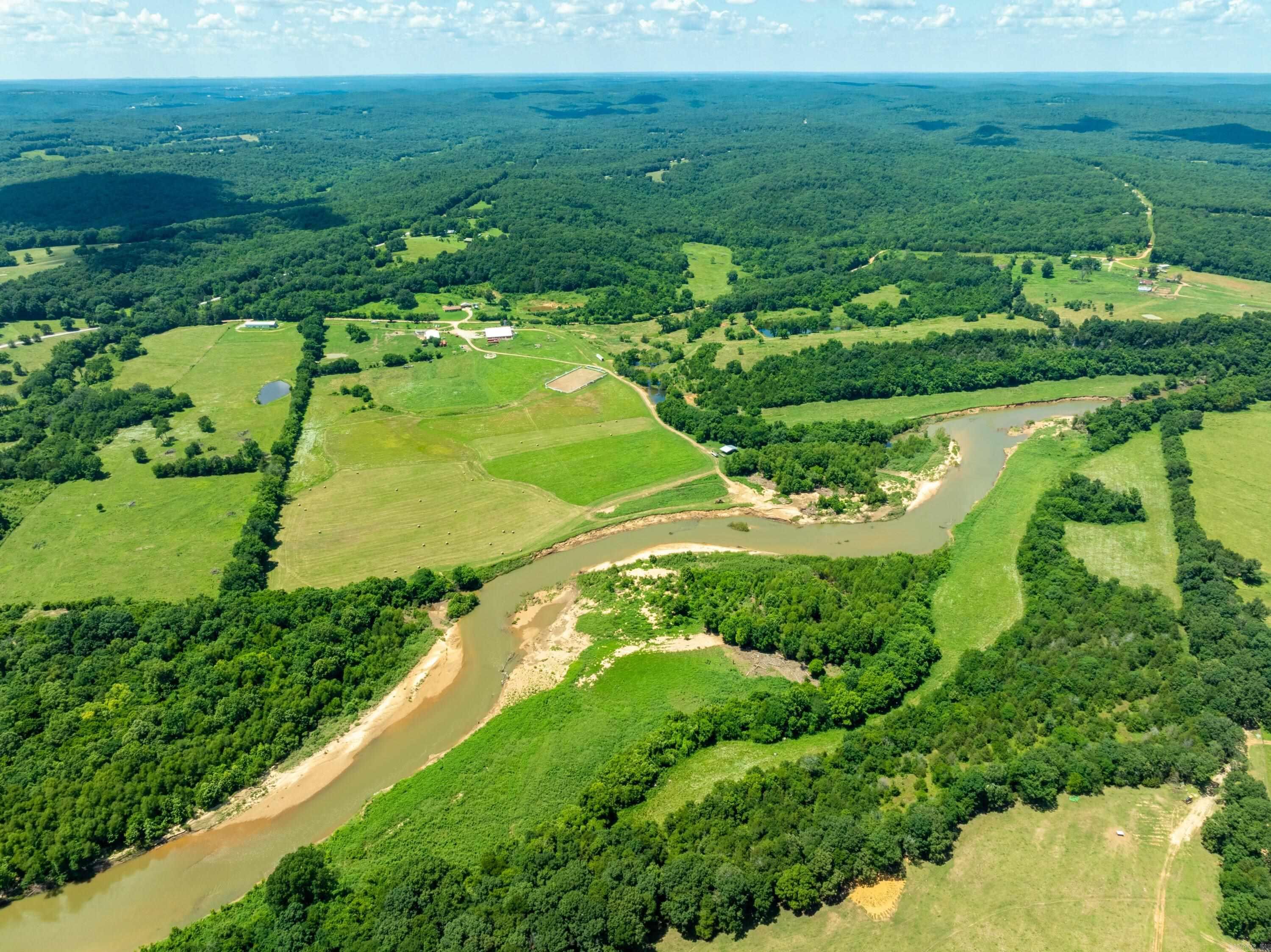Ultimate Ozark Riverfront Retreat – 200± Acres with Barn, Arena, Shop & River Frontage Over 4,000 ft of Strawberry River frontage—sandbars, fishing, swimming, kayaking & rock cliffs—this Sharp County gem is a dream for outdoor lovers! Approx. 75 % hay fields producing 250–300 bales/year, some mature woods for hunting (deer & turkey), ATV trails, and cross-fenced pastures with some goat fencing. A massive 9,000+ sq ft barn features spray foam insulation, large fans, horse stalls, a tack room, toilet room & living quarters. Lower level is handicap accessible with oversized bedrooms, each with custom tiled roll-in showers, roll-under sinks, mini-split HVACs, and windows facing stalls. Main floor offers 3 beds, huge laundry (2 washers/dryers), and a common area. Upstairs includes a full kitchen, living area, balconies, and 4 more private bedrooms with private baths & stall views. Working arena, equipment shop with lift, creek frontage on both sides, only ¼ mile off gravel road. NAEC electric, NEXT fiber internet, Grange Calamine water. Perfect for a horse facility, lodge, retreat center, or private estate—this rare property blends luxury, functionality, and unmatched natural