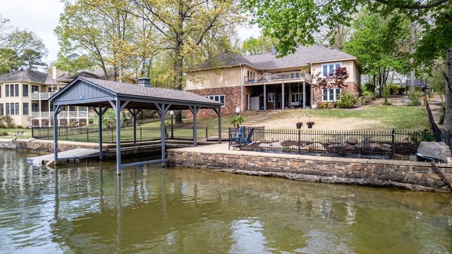 Welcome to 104 Blue Heron Drive.  Situated on a quiet cove with 95 feet of lake frontage, just minutes to the main channel, this beautiful lake front property with a single stall boat slip located inside a gated community is everything you are looking for.  Walk in the front door to a vaulted ceiling with windows galore overlooking your spacious deck that offers distant views of the lake.  4 large bedrooms and 3 - 1/2 baths accommodate your entire family and friends. The large master suite has a sitting area and opens to the deck. A large guest room and bath downstairs is perfect for guests.  Huge game room and kitchenette.