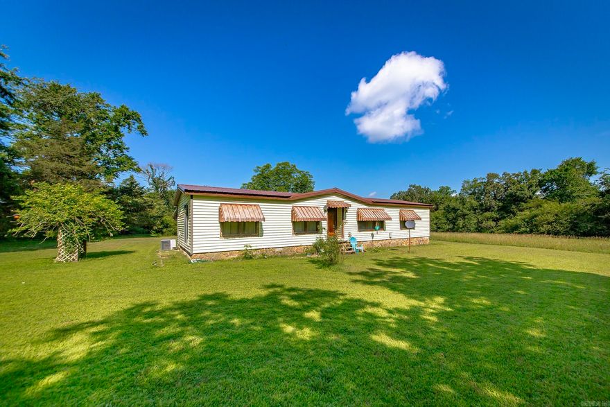 Escape to peaceful country living with this cozy 2-bedroom, 2-bath home situated on 5 beautiful acres, complete with a large pond and serene surroundings. This charming mobile home is perfect for those seeking space, privacy, and a relaxed lifestyle. The wood-burning fireplace with stone accents adds a warm, rustic touch to the inviting living area. Recent updates include new laminate flooring in the living/dining area and new sliding glass patio doors. A newer metal roof was installed in 2021, providing added peace of mind. The spacious primary suite features a built-in electric fireplace and a large bath with double vanities, a garden tub, and mirrored sliding closet doors. The entire property is fully fenced, with a separate fenced-in pen area ideal for pets. Additional features include a storage building and a storm cellar in the backyard. This property is a must-see for anyone craving a quiet country setting with room to roam!