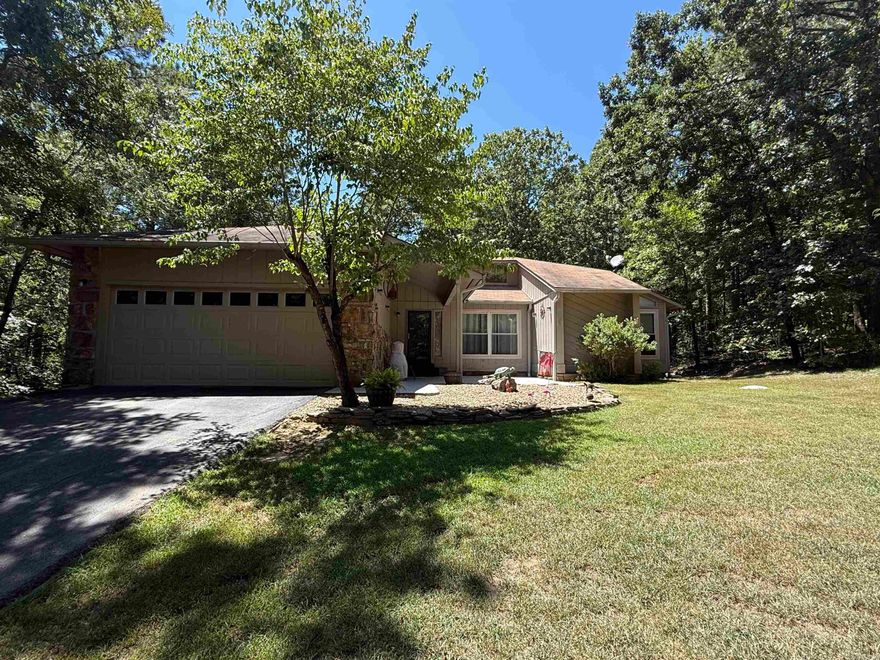 CUSTOM HOME has unique glass solarium built in for all of a peaceful reading nook or plants!  Open Living-Dining area with woodburning fireplace, built-in china cabinet and bookcase.  Also a small sitting area, perfect for reading & a cup of coffee, has new wood flooring. Other flooring is LVP, wood, & tile.  Nice kitchen has all appliances included (refrig/freezer, dishwasher, wall oven, smooth top stove, trash compactor) and an eat-in area with large window that views a wooded area.  Lots of cabinets, pantry, built-in desk.  Master suite has walk-in closet & barn doors to  bath with shower.  New (6/25) back deck looks into woods.  HVAC replaced in 2023.  Windows and doors have been replaced.  Large garage and walkway to front door have new concrete composite epoxy coating.  Fireplace has been inspected, cleaned, and has a NEW cap.  The guest bathroom has a jetted tub/shower, selling AS IS.  **Some furniture is negotiable**