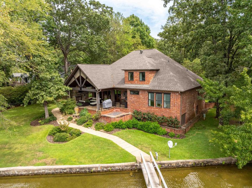 Charming Lake Hamilton Retreat on Bayshore Drive: Welcome to 480 Bayshore Drive, a picturesque lakefront gem nestled in the serene landscapes of Hot Springs, Arkansas. This inviting property offers an unparalleled combination of modern comfort and tranquil natural beauty, making it the perfect lake retreat for both relaxation and recreation.  Set on a generous lot with direct access to Lake Hamilton, this home provides stunning water views and a private dock for boating, fishing, and swimming.  The open-concept floor plan features expansive living areas with abundant natural light, highlighted by large windows that frame breathtaking lake vistas. The living room, with its cozy fireplace, and vaulted wood ceiling flows seamlessly into a stylish dining area and a well-appointed kitchen. The kitchen is a chef’s dream, equipped with high-end appliances, granite countertops, and a large island perfect for meal prep and casual dining.  The property includes 4 generously sized bedrooms, each offering ample closet space and easy access to modern bathrooms. The master suite is a tranquil haven with its own private view overlooking the lake.  Step outside to enjoy a large flagstone patio wit