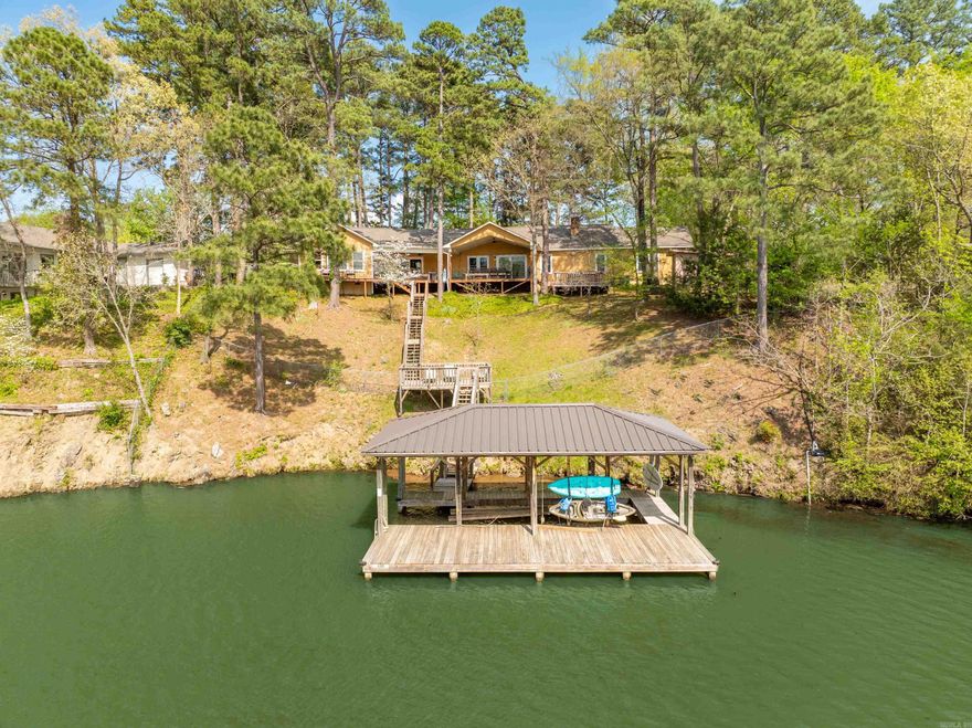 This home is more than just a retreat—it’s also an incredible income-generating short-term rental opportunity. Welcome to this stunning one-level lakefront home offering 5 spacious bedrooms, 4.5 bathrooms, and unmatched indoor-outdoor living. From the gated driveway and circle drive to the fully fenced yard, every detail is designed for comfort, privacy, and enjoyment. Originally expanded in 2009 with a custom addition by David French Architect, the home features beautiful Brazilian walnut floors in the kitchen, family room, and hallway. The open kitchen includes a breakfast bar perfect for casual dining or entertaining guests, while the oversized laundry room adds extra convenience. Step outside to a huge covered deck with breathtaking views of the lake and surrounding mountains—ideal for relaxing or hosting gatherings. Enjoy lake days with your own covered boat dock equipped with a lift, or unwind in the private hot tub after a day of fun. Enjoy the a game room, extra living space, generator, front yard sprinkler system, and a gated entrance for added security. Whether you're looking for a personal waterfront haven or a smart investment, this home delivers it all!