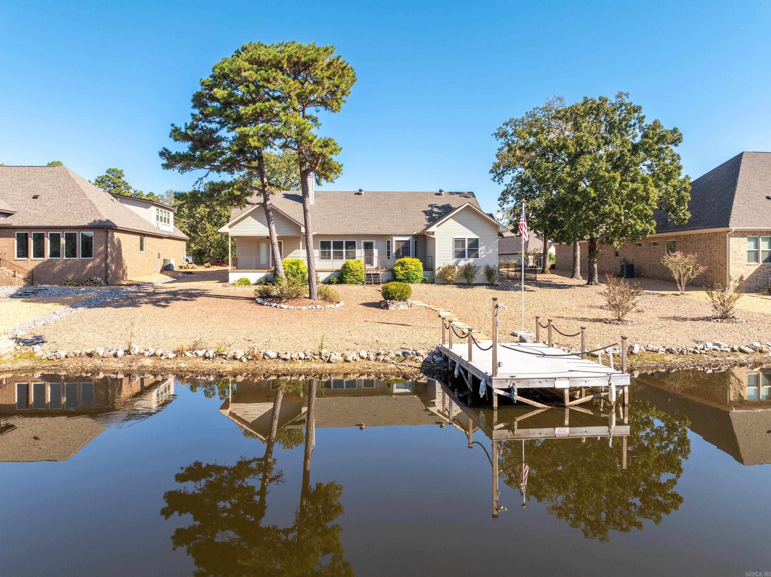 Welcome to 34 Linares Ln, a charming lakeside retreat in Hot Springs Village! This beautiful 3-bedroom, 2-bath home offers stunning views and a serene atmosphere. The bedrooms are spacious and inviting, perfect for relaxation. There are two well-appointed baths featuring modern amenities. The large living area is a bright and airy open layout, ideal for entertaining and family gatherings. Enjoy your morning coffee or evening sunsets on the expansive back porch overlooking Lake Maria. Take advantage of your private swim dock, perfect for swimming, fishing, or just soaking up the sun. Located in a tranquil golf community, this home is a perfect blend of comfort and outdoor living. Don’t miss your chance to own this lakeside paradise!