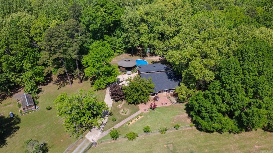 WOW, this very unique one of a kind home sits on 40 beautiful Acres. Long private drive  to gate then the property opens up-Home sits at a distance in a tranquil setting. Enjoy outdoors w/Beautiful Landscape, gorgeous Gazebo, above ground pool w/deck, brick paver sidewalks, sitting areas...  Enclosed front porch (2003) into a sunroom/office area. LR has very unique features including tall ceilings with Beams & amazing wood work, wood burning FP and built ins to display all the unique home décor. Nice updated kitchen with Island, lower cabinets have drawers for easy access to your cookware.  Large Formal Dining allows you space for large family or quest dinners. Unique Spiral staircase takes you up to a loft bedroom with big closet. But the real show stopper is the Master suite/Bath, you have to see it to believe how large the walk in shower is, Double sinks with grand finishes and large enough for a Sofa and attached to the laundry room for ease. Home also includes a mudroom w/ 1/2 bath, basement storage area... New Roof Oct, 2025. 2- New HVAC's 2025. 40x80 Barn, 24x24 shop, 10x16 she shed-potting, 2 stocked ponds, heated Greenhouse,16x70 mobile (2nd residents) and much more.