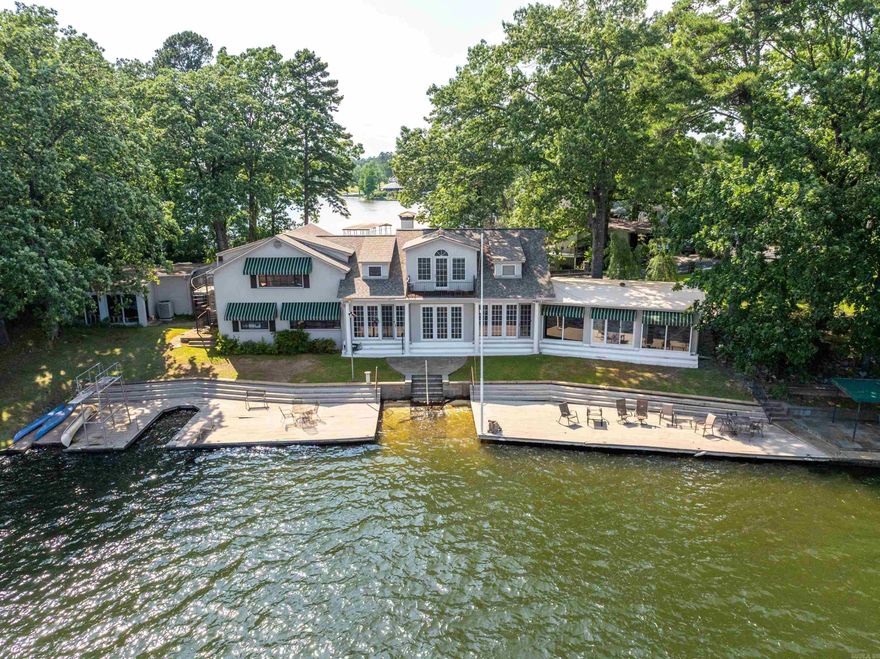 Come see this once-in-a-lifetime property perched on the shores of Lake Hamilton in Hot Springs, Arkansas! Situated on a majestic  point, this extraordinary estate offers unparalleled breathtaking views of sunrises and sunsets on Lake Hamilton's serene waters. Whether sipping your morning coffee or hosting guests for dinner, you will be captivated by the natural beauty that is right outside your door. With plenty of area for outdoor living, you can enjoy direct access to the lake waterfront. Recreation and entertainment spaces are abundant with outside decks hovering right over Lake Hamilton. Dive into the serene waters from your own “high dive” board, moor your watercraft, or soak up the sun and take in the spectacular views that stretch for miles. The waterfront boathouse with two private slips is perfect for facilitating easy access to all sorts of water activities, including skiing, fishing, or leisurely cruises to soak up the sun. Spacious interiors abound in the 5-bedroom, 3-bath home, which spans 4992 square feet. Luxury details are evident throughout with vintage finishes and tasteful furnishings that enhance its ambiance.