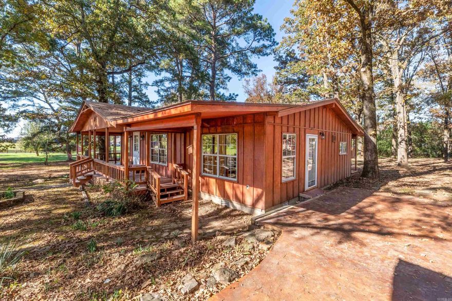 Charming 1,520 sq. ft. home situated on 1.5 acres. The home offers 2 bedrooms and 2 bathrooms with original wood floors. Vaulted ceilings enhance the main living area, creating an open feel with abundant natural sunlight. Large windows provide bright interior spaces and views of the surrounding yard and mature trees. The kitchen features handmade custom cabinetry and a propane gas range. Exterior features include a wraparound covered front porch extending along two sides of the home, as well as a deck positioned on two sides for additional outdoor living and entertaining space. The yard is established with seasonal bulbs and mature crape myrtles, providing color throughout the year. Located in the Greenbrier School District, 5 minutes to Wooster, 10 to Greenbrier, 20 to Conway, 35 to the Ozark foothills, and 40 to Little Rock. Also listed with 20 acres MLS 25045176