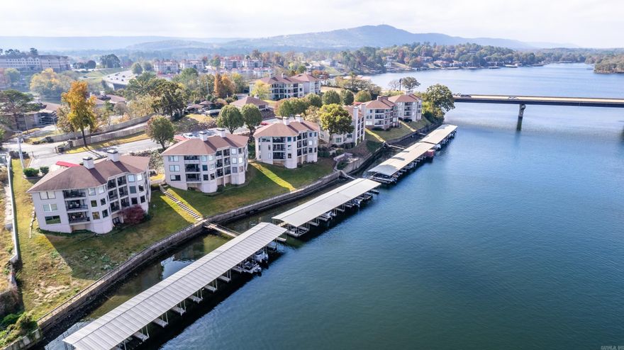 Beautiful lakefront condo with gorgeous lake views of the main channel on Lake Hamilton. You also have a perfect spot by the Hwy 7 bridge to enjoy front row seats of the seasonal fireworks displays and the great mountains views. Grounds are beautifully landscaped. Gated entrance for extra security. Fire Sprinkler system installed in the condo. Condo comes fully furnished and is ready for Nightly Rentals. Wake up every day to these views from the master bedroom, the living room, kitchen and even into your dining area. Two spacious decks to sit outside and enjoy your coffee with a view! Your boat dock and slip are right below the condo for easy access and is within your view. Condo comes with a designated storage area for your boat supplies and pool toys. Pool, Hot tub and Community Room is walking distance from the condo. There is grilling area with tables for outdoor dining right beside the pool. Condo is located by several local restaurants, and minutes from Oaklawn Resort Casino/Racetrack. *Update* Seller has allotted up to 10K (With an acceptable offer) Buyers choice of new flooring for the condo, OR can use up to that amount to go towards HOA fees.