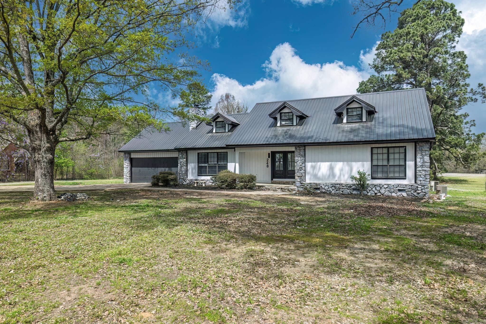 This beautifully remodeled 4-bedroom, 3-bath home sits on 1.23 acres, offering the perfect blend of modern elegance and comfort. The master suite on the main level features a luxurious walk-in shower, while the stunning waterfall quartz countertops add a touch of sophistication to the kitchen. A spacious laundry room includes a convenient dog bath, making pet care a breeze. The home also boasts a two-car garage and a whole-home generator for added convenience and peace of mind. Upstairs, you'll find a generous game room, two additional bedrooms, and a full bath, providing plenty of space for family and guests. The living room is warm and inviting with a gas starter fireplace, while the dining room flows seamlessly into a sunroom or office space, perfect for work or relaxation. The modern stairwell in the entryway adds a striking design element, setting the tone for the home's stylish interior. With a durable metal roof and thoughtful updates throughout, this home is both stunning and practical.