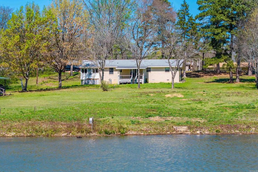 100’ of Lake Hamilton Frontage in Lakeside Schools for $365K — Opportunity Knocks. Opportunities like this are increasingly rare, with many lakefront lots alone now approaching this price point. The brick home with a durable metal roof sits on 100 feet of accessible shoreline in the sought-after 7-South area. Located outside the city limits in an unrestricted subdivision, the possibilities are wide open—from renovating the existing home to building a second residence closer to the water for even greater investment potential. A current permit is already in place for a 95’ boardwalk wrapping the shoreline and a two-stall covered stationary boat dock, setting the stage for exceptional lakefront living. Inside, the home features an open living, kitchen, and dining area that flows to a covered porch overlooking beautiful water views. Coupled with the spacious back porch, a versatile bonus room with private entrance connects to the primary bedroom adding flexibility for guests or entertaining. Enjoy water views from nearly every room in this prime 7-South location. Please note: the home is a fixer-upper, HVAC has been removed, and utilities are currently off.