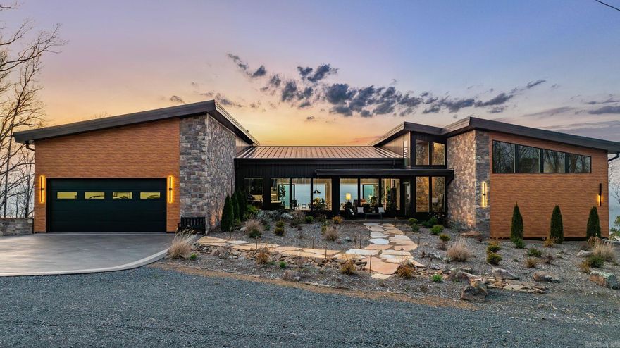 Designed by Polk Stanley Wilcox Architects and engineered into one of the Ozarks' most commanding ridgelines, this generational contemporary estate on twelve private, gated acres above the vast horizon of Greers Ferry Lake redefines what luxury in Arkansas can be. Built to endure for generations — thirty tons of steel, 350 yards of concrete, hand-laid natural stone, and floor-to-ceiling glass framing unobstructed panoramic views from nearly every room in the home. More than 6,500 square feet of exceptional turnkey living unfolds beneath soaring knotty pine ceilings and exposed steel beams. The chef's kitchen is appointed without compromise, centered on a stunning book-matched marble island. The primary suite offers a thermal air soaking tub, private fireplace, and uninterrupted lake views. A commercial fitness suite, sauna, whole-home automation, whole-home audio, storm shelter, and whole-house generator complete an offering that stands entirely without parallel in this market.
