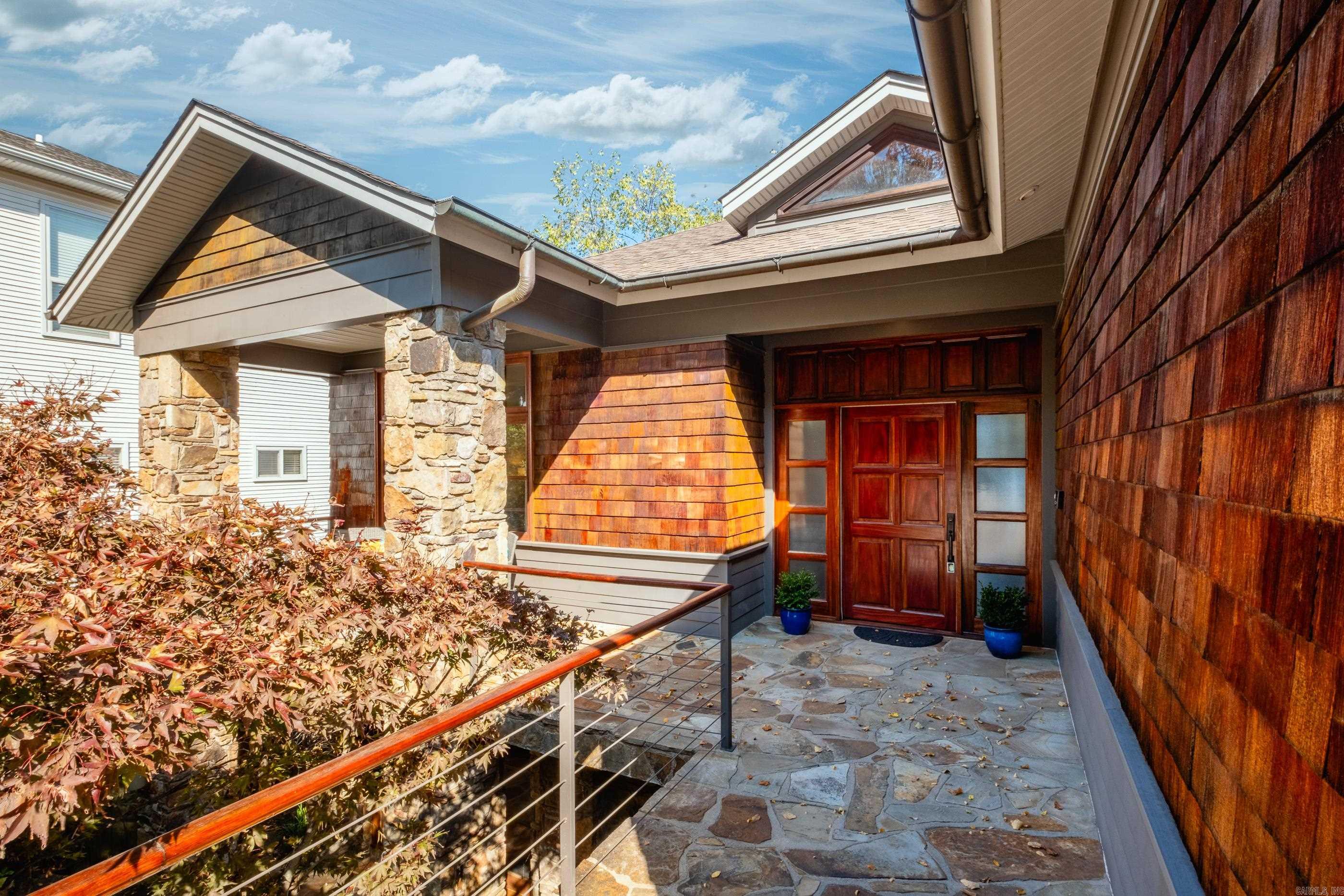 Welcome to Edgerstoune Lane, where contemporary design seamlessly blends with artisanal craftsmanship. This private street with a small POA is adjacent to Knoop Park and just minutes from downtown & area hospitals. Located in the popular Hillcrest neighborhood, the impressive stonework waterfall & koi pond complement the rich blend of stone & Brazilian Cumaru wood that create an inviting exterior that sets the tone for what lies within. Inside, abundant natural light showcases the stunning custom wood mantel, custom cabinetry and impressive wood ceiling details by Keith Newton. Additionally solid Brazilian Cumaru wood doors, trim & flooring enhance every room. Designed for comfort & entertainment, this residence features two balconies with breathtaking Arkansas River Bluff views. The kitchen is a culinary enthusiast's paradise, boasting custom walnut cabinets, a Sub-Zero fridge & high-end appliances, along with a butler's pantry. The versatile lower level includes two bedrooms, a den, workout room, a large bonus room and a kitchenette making it perfect for a guest suite or home office space. Ample storage & built-ins throughout. This home offers the best of luxury & practicality.