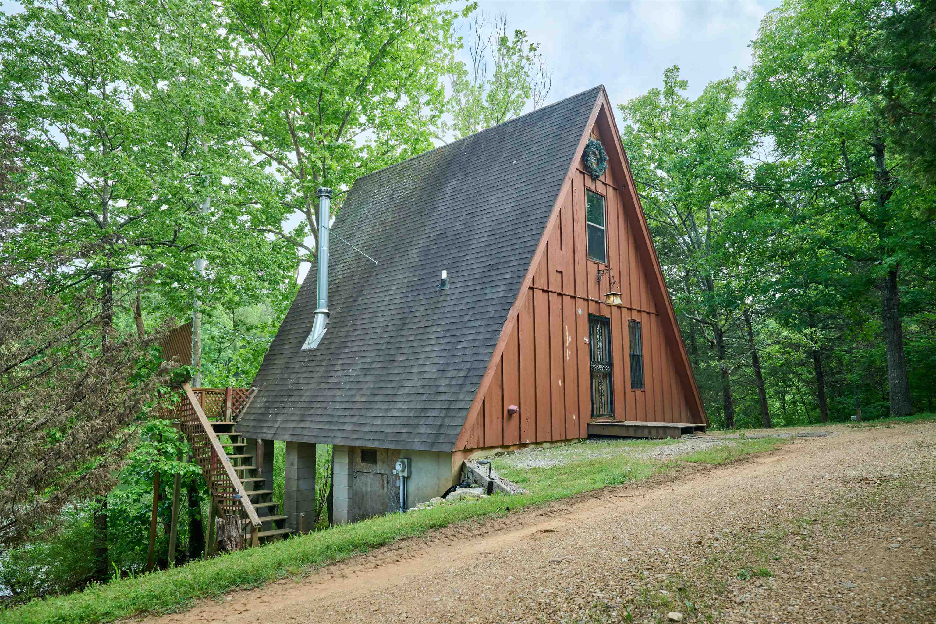 OZARK MOUNTAIN LAKE CABIN!! This lake cabin is nestled among the trees on a spring fed lake....It could be your private A-frame cabin in the tree tops. It is located on about 1/2 acre-perfect for a cozy style of resort living. Features: a rustic northwestern motif throughout, floor to ceiling window/doors allowing a great lake vista, soaring vaulted wooden ceiling, easy care plank flooring, kitchen island, granite counter tops and lake side deck for entertaining. On the main level is the great room/dining area, kitchen, and bath. The loft bedroom upstairs has a spectacular lake view. Included with the property is a joining wooded lot affording plenty of privacy and plenty of nature & wildlife. The private dock offers easy access to launch canoes or paddle boards, paddle boats and perfect for fishing. There are other updates/upgrades. Spring River and South Fork River are near by-for canoeing, rafting & trout fishing. This charming a-frame cabin is priced right to sell and probably won't be on the market very long. Call listing broker for more details and information.