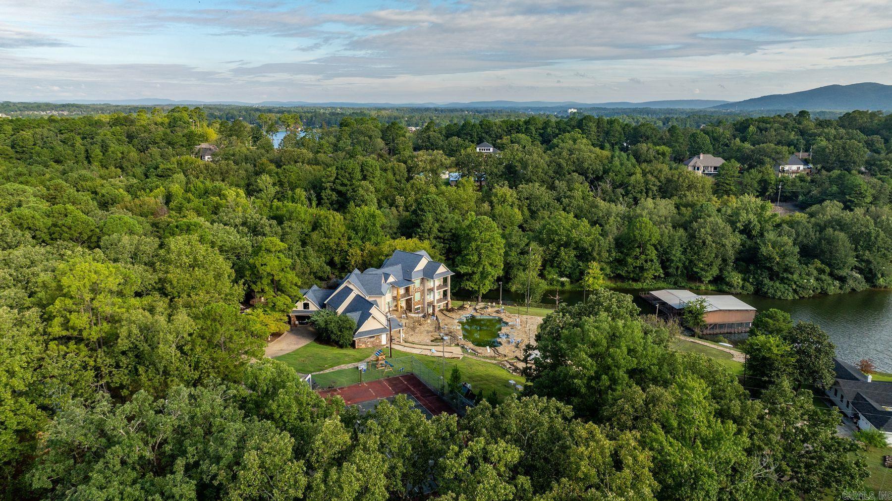 Extraordinary opportunity to own a storied property in a highly desirable Lake Hamilton location. This rare offering spans 7+ acres with approximately 695 feet of road frontage and 350 feet of lake frontage on the north facing shoreline. A canopy of mature trees creates a private, park-like setting, while the curved driveway and gated entry set the tone for a truly remarkable estate. The property features a 5-slip boat dock, a stone-lined gunite pool, and a tennis court, each waiting to be restored for future enjoyment. With sweeping lake views and endless possibilities for reimagining, this estate invites you to create a bespoke, legacy retreat for generations to come. Home to be sold āAs Is.ā