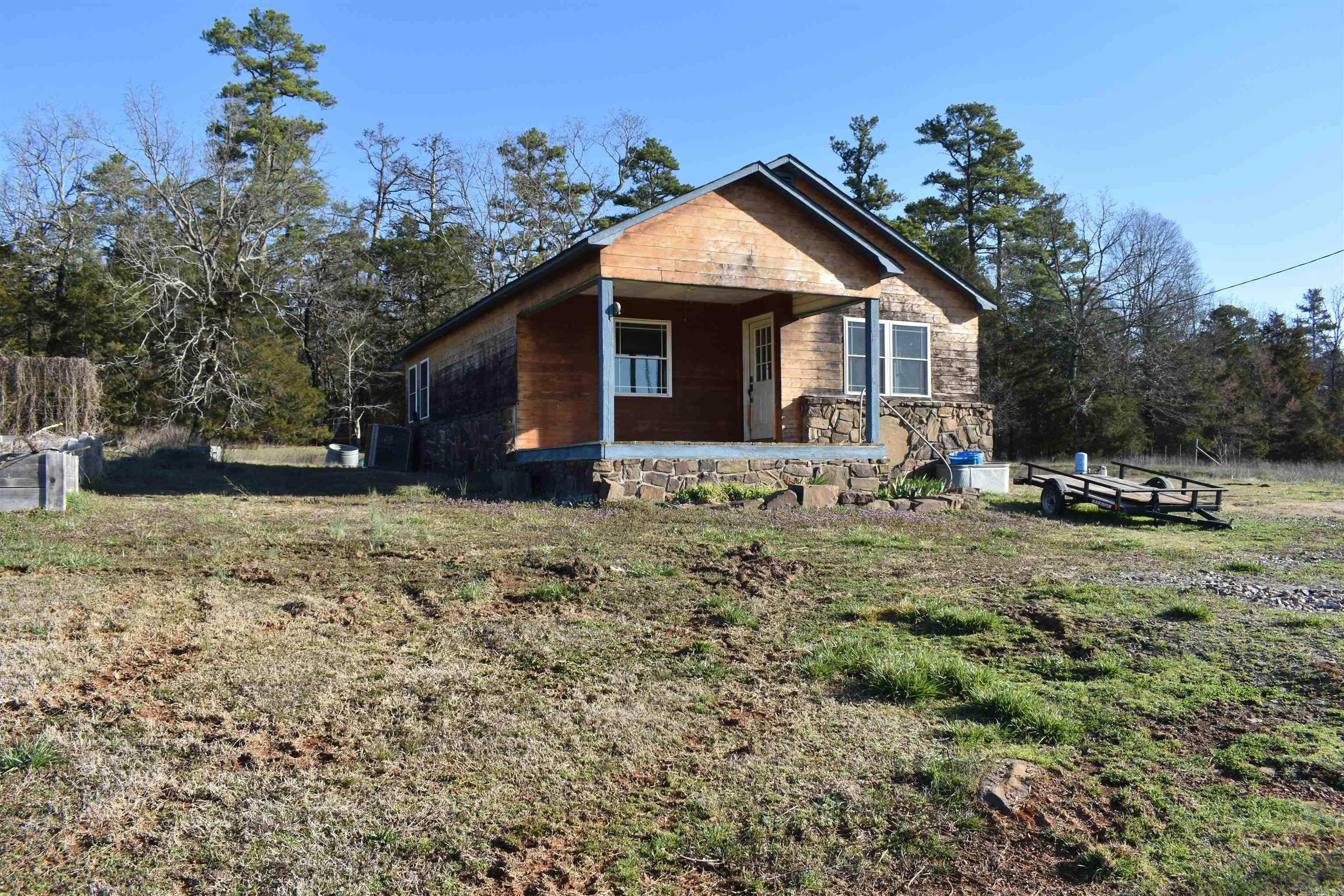 Located in rural Scott County adjoining the Ouachita National Forest, this 94 +/- acre homestead is perfect for a farm or a recreational property! The 94 +/- acres sprawls across mostly flat and gently rolling terrain, with the majority of its acreage being in pasture. The fenced and productive pasture is broken up by strips of woods and seasonal creeks flowing through the property to the nearby Fourche LaFave River. The pasture has been used for grazing cattle and hay production, as well as deer and turkey hunting. Water lines for water troughs have been ran throughout the property, and are in place for additional cross fencing to be added to the farm. A large open span hay barn is located just down the hill from the property, giving ample storage for hay and equipment. The stylishly renovated farmhouse sits atop a small hill facing the mountains to the south. The panoramic views of the Ouachita Mountain range that are offered from the front porch are nothing short of first class. Inside you’ll find a cozy living space accompanied by three bedrooms and one bathroom. This home is move in ready, and is even wired with fiberoptic internet.