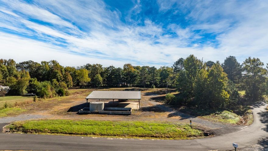Approximately 4 +/- acres including added features of an open metal-roofed structure with a concrete pad, a small storage/utility shed (10x12) and has electric and water, and a fiberglass water tank (6000 GAL) — perfect for a workshop, storage site, or business use.  Property sits on a level lot with paved road frontage and easy access to Highway 65. Included in the sale is a separate wooded one-acre parcel located down the road (see pictures for approx. location)   Conveniently located across Highway 65 from Goode’s Cash Saver and Snappy’s in Damascus offering excellent visibility and convenient access.