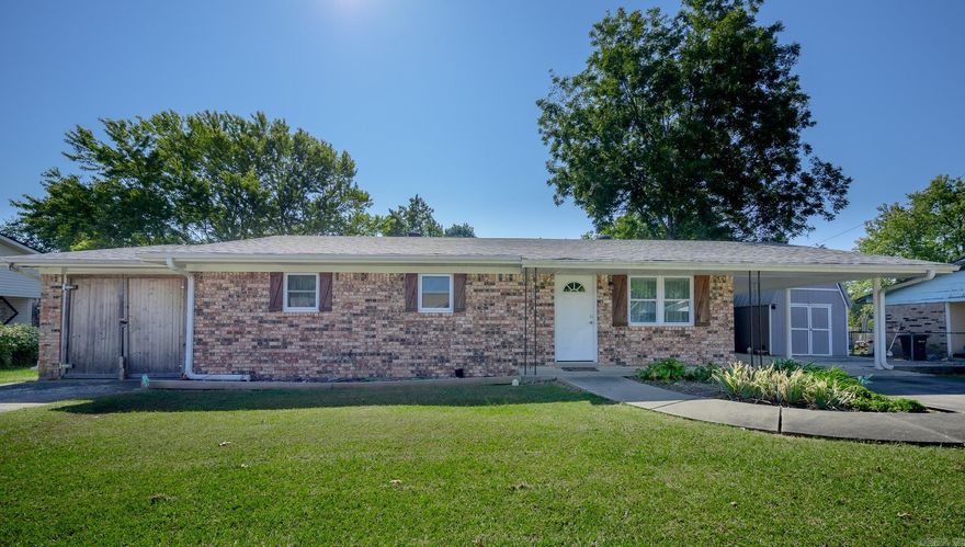 This bright and inviting brick home features a beautifully landscaped front yard. Upon entering, you'll find a spacious living room, a fully updated kitchen with new appliances, a laundry closet, three bedrooms, and one and a half bathrooms. Step out to the covered back patio, where you'll discover a private area complete with a dog run and pet access to an outbuilding that is equipped with air conditioning for your pets' comfort. The generously sized backyard includes a second storage building and ample space for your favorite activities. Additionally, a third outbuilding with decking is located next to the carport and also has an air conditioning unit.