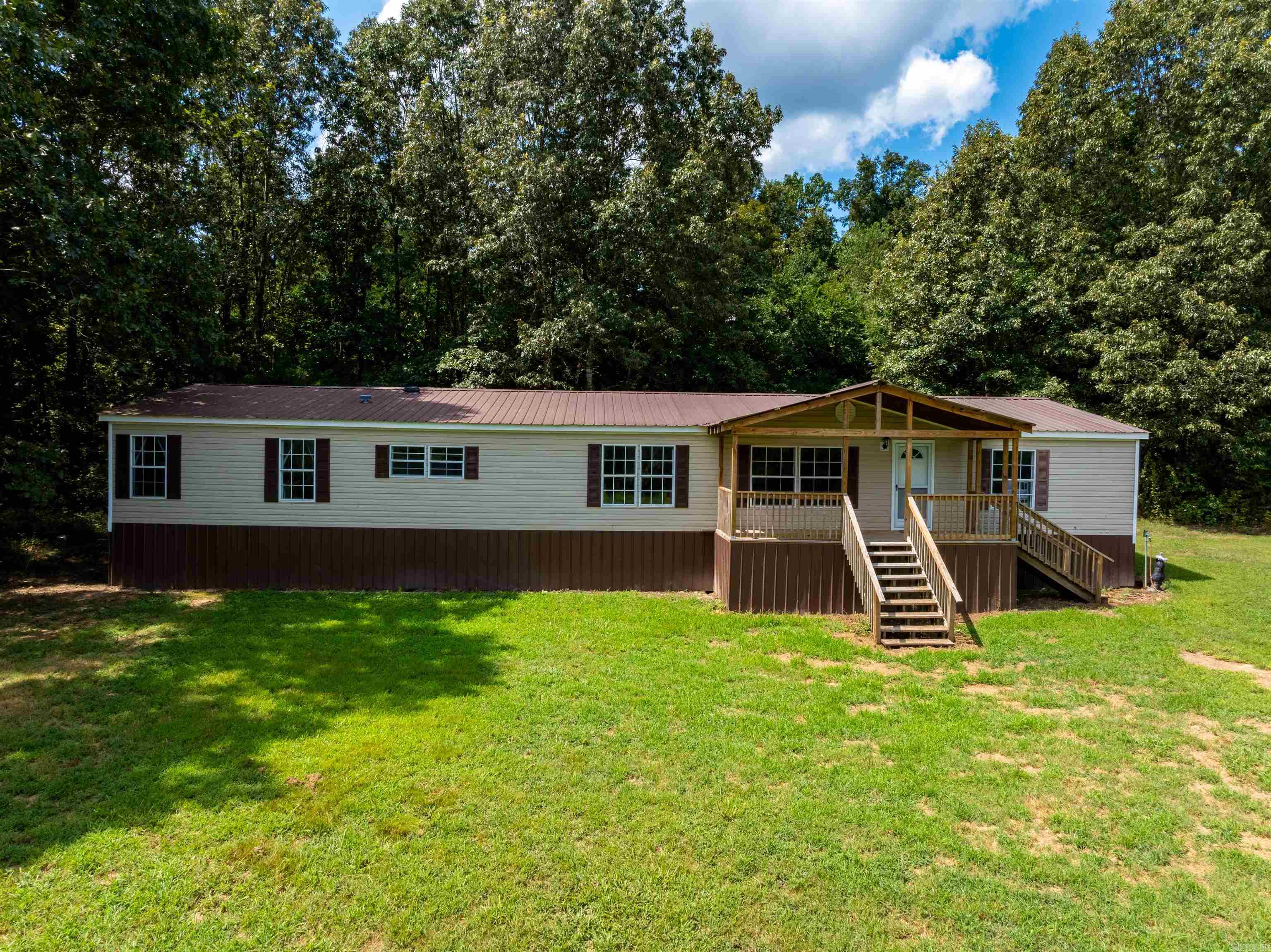 Spacious 4 bed, 2 bath double-wide mobile home on approx. 4.25 acres just minutes from Cave City, AR, on paved Grange Road. This 2,000+ sq ft home offers an open layout perfect for families, first-time buyers, or investors seeking a rental near town. Features include a large living room filled with natural light, a separate den with a fireplace, and a massive kitchen with island. The dining area opens to a back deckāperfect for grilling and enjoying Ozark sunsets. The oversized laundry/mudroom offers extra storage. Split floor plan with private primary suite featuring a soaking tub, walk-in shower, dual closets (including a walk-in). Secondary bedrooms are separated for added privacy. Move-in ready with only cosmetic updates needed. The land is mostly open and ideal for kids, pets, a garden, or a few animals. Located in a quiet rural setting with easy access on a paved county road. Minutes to schools, stores, and town amenities. New survey completed and title is in hand.