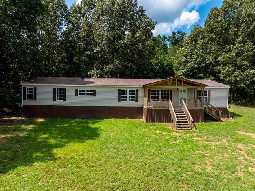 Spacious 4 bed, 2 bath double-wide mobile home on approx. 4.25 acres just minutes from Cave City, AR, on paved Grange Road. This 2,000+ sq ft home offers an open layout perfect for families, first-time buyers, or investors seeking a rental near town.  Features include a large living room filled with natural light, a separate den with a fireplace, and a massive kitchen with island. The dining area opens to a back deck—perfect for grilling and enjoying Ozark sunsets. The oversized laundry/mudroom offers extra storage.  Split floor plan with private primary suite featuring a soaking tub, walk-in shower, dual closets (including a walk-in). Secondary bedrooms are separated for added privacy. Move-in ready with only cosmetic updates needed.  The land is mostly open and ideal for kids, pets, a garden, or a few animals. Located in a quiet rural setting with easy access on a paved county road. Minutes to schools, stores, and town amenities. New survey completed and title is in hand.