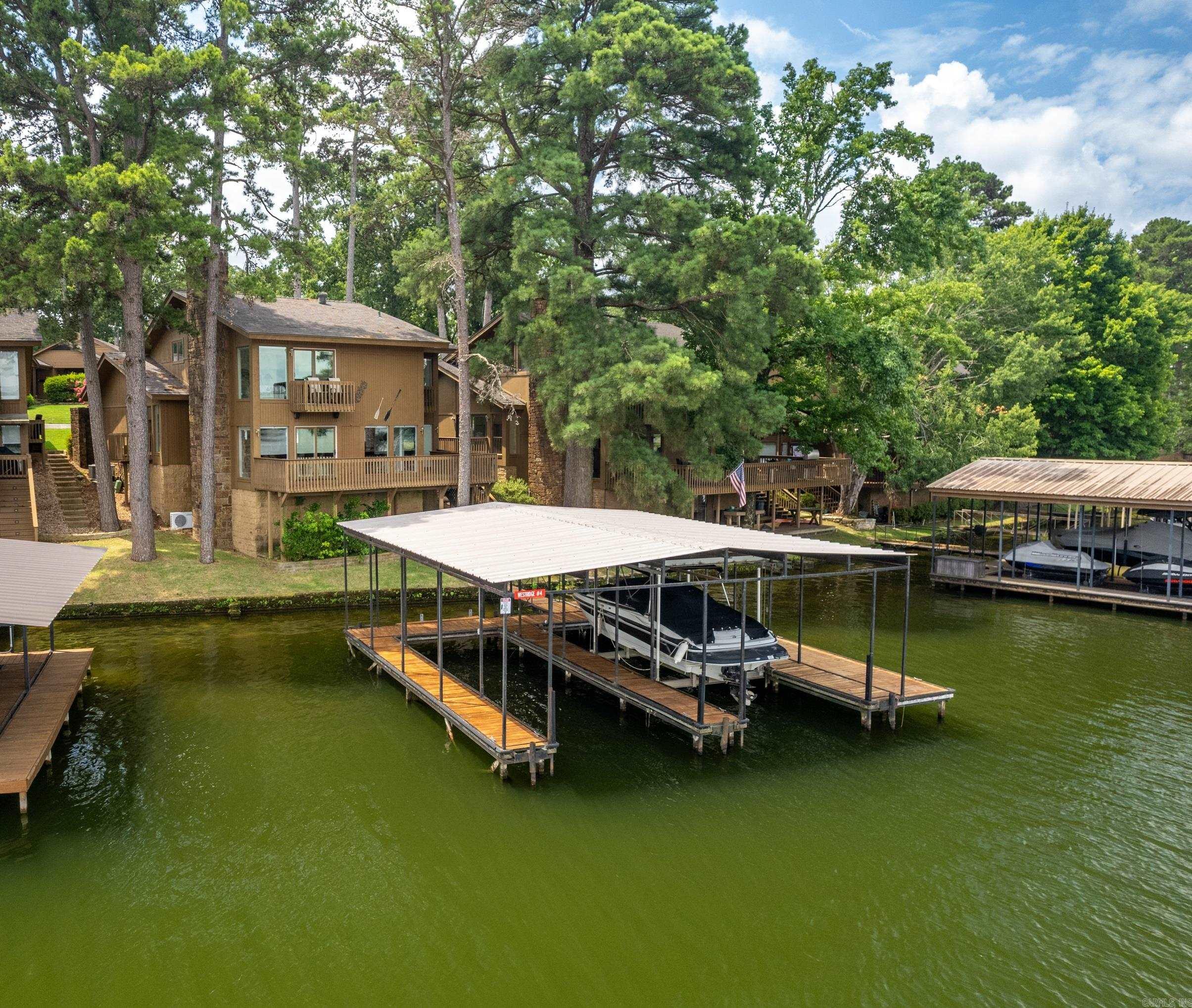 Welcome home to the luxurious Westridge Condos, a private, gated community on Lake Hamilton with swimming pool, clubhouse and onsite property manager. One of the very limited stand alone condos in Hot Springs, this split level unit offers gorgeous views of the lake at every turn, several decks, a 2 car carport, and lots of storage both inside and out. The fabulous fixed, covered, 2 stall boat dock is larger than most and able to accommodate the boats of today. It also comes with a newer lift that's only about 3 years old. All 3 bedrooms have an ensuite bathroom (one has a walk in shower, one has a walk in shower & tub, and another has a shower/tub combo) and the primary walk in closet is incredible! Bonus room upstairs currently being used as a bedroom could also be an office. Beautiful, modern kitchen with solid surface counter tops, pantry and breakfast bar, cozy living space with fireplace and the most unique bar area with glass display top cabinet. Don't make the mistake of letting this one slip through your fingers. Make your viewing appointment today!