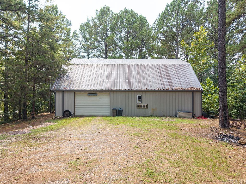 Are you in search of a secluded residence nestled among five acres of majestic pine trees, with convenient access to Lake Ouachita and various recreational activities, all within a 45 minute drive to Hot Springs? This home and shop may be the perfect solution for you. The shop encompasses approximately 2,500sqft, featuring living quarters on the second level, which includes 1,500 +/- sqft of open concept living space. This area, with fresh, grey paint, comprises an eat-in kitchen, 3 bedrooms, 2.5 bathrooms, and a utility room. The shop offers ample space for vehicles, SUVs, and boars, along with a heated and cooled office equipped with a half bath. It is wired with 220-volt power and adequately lit, making it ideal or automotive projects, recreational activities, or other pursuits. With 5 acres of land, the property also presents opportunities for investment projects, such as rental storage units or short/long term stays. A small, year-round creek runs along the southern edge of the property, enhancing its charm. Given its proximity to Lake Ouachita, alone with nearby fishing and hiking trails, the possibilities for this property are truly limitless.