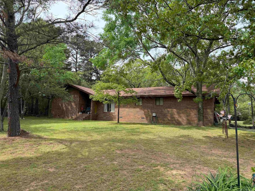 Getaway to country living on 2.75 acres with two shops and a 3 bedroom, 2 bathroom brick home.  Beautiful mature trees on all sides of the property with an open area ideal for gardening.  The home has a formal dinning room with build-ins and a back patio for relaxing.  Wood burning insert/fireplace in the living room.  New roof in 2023.  Come and check out this great opportunity outside of city limits and no restrictions.