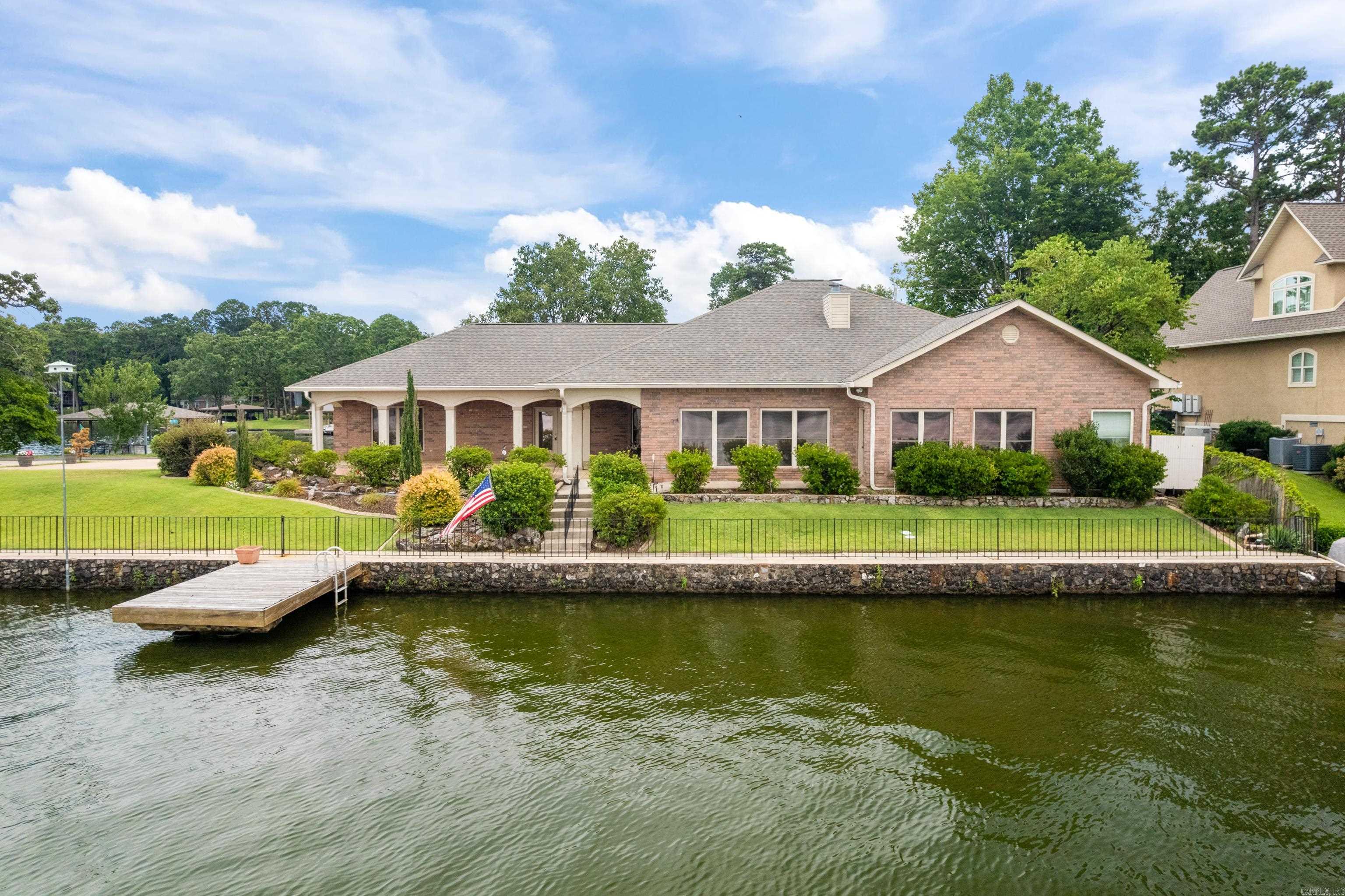 Lakefront Luxury on Lake Hamilton! This exquisite 4 Bed, 4 Bath home offers exceptional lakefront living. The gourmet kitchen features granite countertops, a built-in ice maker, and an expansive walk-in pantry. The living room boast beautiful built-ins with a combined wet bar, and a striking gas log fireplace. Enjoy the convenience of two master suites, each with generous walk-in closets. One master includes a jetted garden tub with a breathtaking lake view, while the second offers an additional washer and dryer hookup. The office space features custom built-ins, providing a versatile foundation to personalize the area to your specific needs. Throughout the home you'll find elegant planation shutters and crown molding. The exterior is a true oasis, showcasing meticulous landscaping, panoramic lake views, a swim dock, and a double boat slip with lifts. One for a party barge and one for a ski boat. Additional amenities include a sprinkler system, whole-home generator, and ample extra parking. Call to schedule your private showing today!