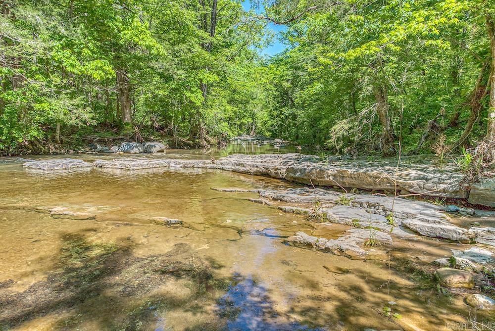 This stunning Ozark property is a rare gem, offering a wide range of features on an unforgettable landscape. It boasts a crystal-clear, spring-fed 2.5-acre lake with bluffs perfect for camping, fishing, and swimming. The land also includes over a mile of frontage along Bens Branch Creek, just before it meets Cave Creek. Mature hardwood and pine timber provide both scenic beauty and investment potential. With incredible hunting—deer, turkey, black bear—and endless recreational options, this land is a dream for outdoor lovers. It features cleared ATV/UTV trails, hiking paths, and a large cave tucked into the hillside. Two areas have electricity, giving you flexibility for building a home or cabin. The property borders Arkansas Game & Fish land on the north and sits just ¼ mile from thousands more acres of public land. With rolling topography, ridges, oak flats, and peaceful seclusion, it’s perfect for adventure or tranquility. This generational property is a true Ozark treasure.