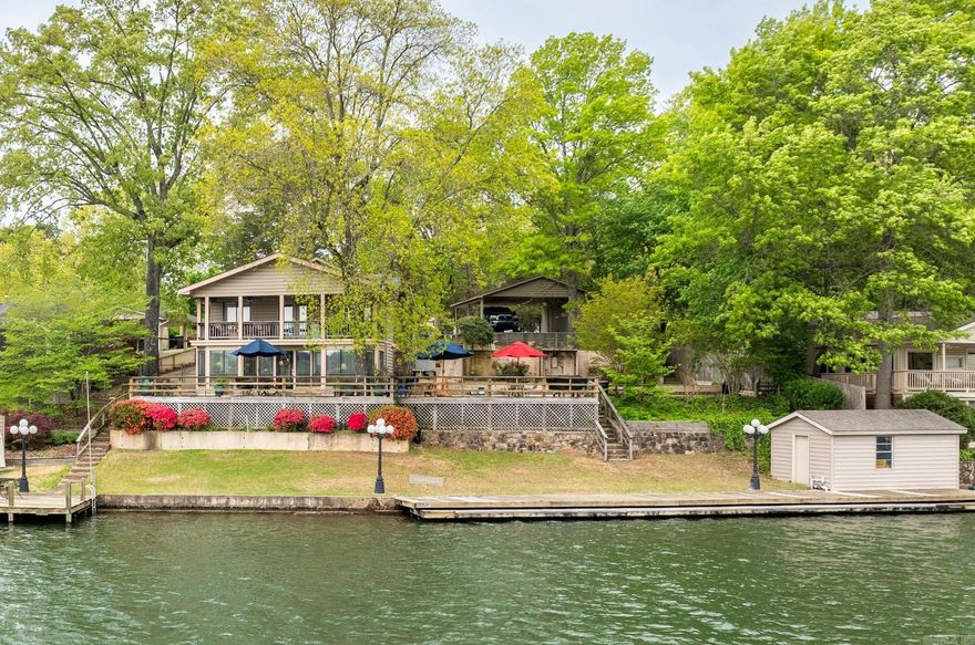Welcome to your dream lakehouse on Lake Hamilton in Hot Springs, AR! This stunning 4-bedroom, 3-bath retreat spans 1,938 square feet and offers many features for lake enthusiasts: Spectacular Open-Water Views: Enjoy 152 feet of shoreline with unobstructed panoramas—perfect for morning coffee or evening cocktails. Private Boat Dock & Lift: A single-stall dock with lift ensures your boat is always ready for cruising, fishing, or watersports.  Expansive Outdoor Living: A 1,224-sq-ft deck wraps around the home, providing multiple seating areas, al-fresco dining, and sun lounging.  Comfortable Floor Plan: Four bright bedrooms, including a lakeside primary suite, and three full baths with vaulted ceilings and wall-to-wall windows. The home sits on one lot, and the side yard is an additional lot, providing options for an extra dwelling.  Ample Covered Parking & Storage: A 22×22 double-car carport plus an additional 624-sq-ft carport with a storage loft—ideal for vehicles and toys.  Versatile Outbuildings: Two outbuildings (12×12 and 13×18) ready for studios, offices, or gear storage. Scenic Boardwalk: A 76-foot boardwalk hugs the shoreline—great for strolls, fishing.