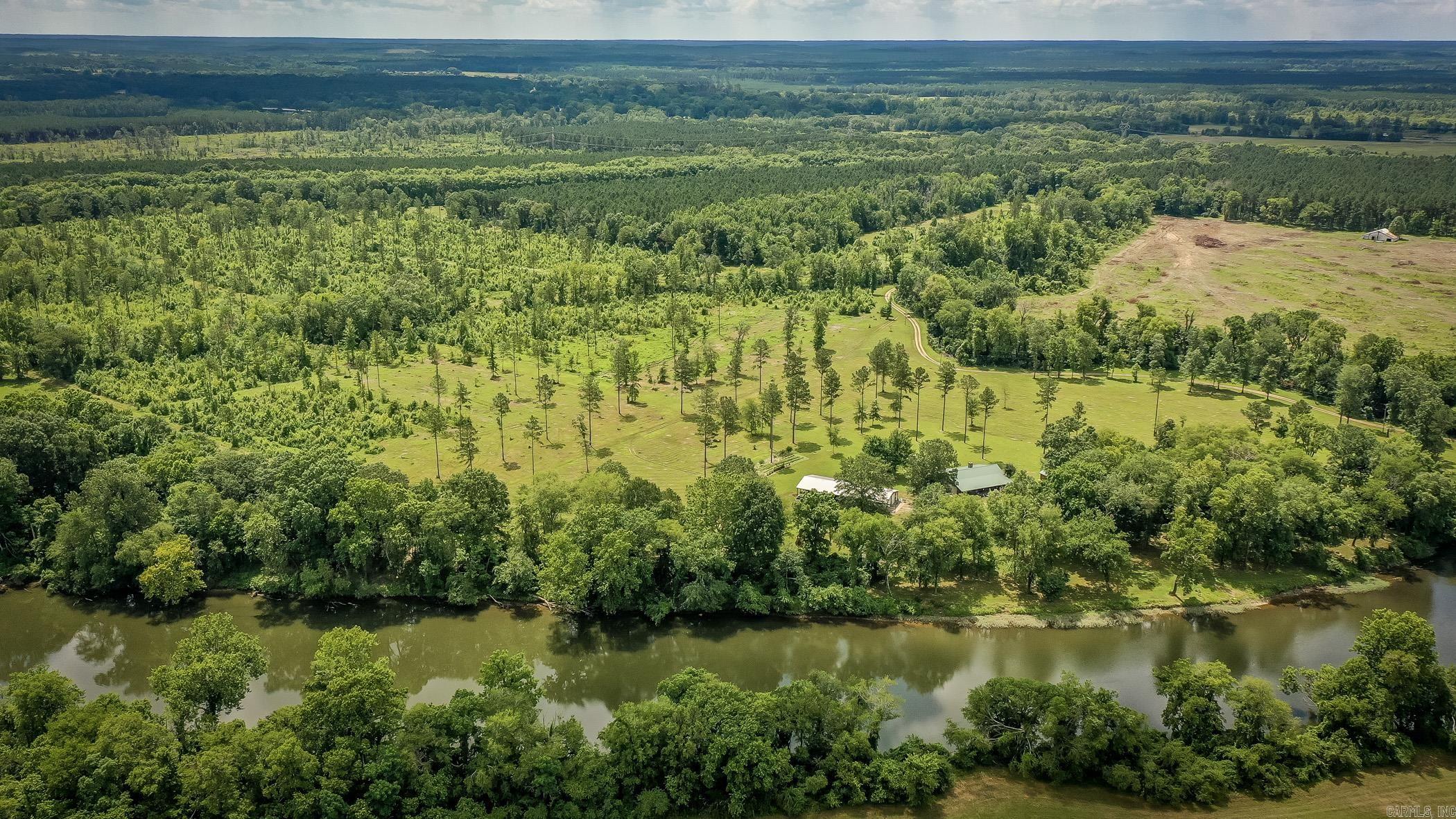 Discover the serene charm of 100 Lake Rd, Donaldson, AR, a property that offers a harmonious blend of natural beauty and comfortable living spaces along the Ouachita River. The exterior of the property extends a welcoming embrace with its lush, green lawn, punctuated by the stately presence of towering trees. These offer not only a majestic view but also a shaded canopy, ideal for outdoor activities or simply enjoying the peaceful riverfront views. The private lake adds an element of tranquility, its still waters mirroring the dense forest standing sentinel along its banks. This space is perfect for those looking to connect with nature, be it through a morning meditation by the water or recreational fishing. Stepping inside, the residence boasts an inviting open-plan living area that seamlessly fuses rustic charm with modern comfort. The eye is immediately drawn to the warm wooden paneling and beams overhead, crafting an authentic and homely atmosphere. The generous living space features ample room for relaxation and entertainment. It is a versatile area that can adapt to host anything from quiet family evenings to lively gatherings. Take a tour of this unique oasis!